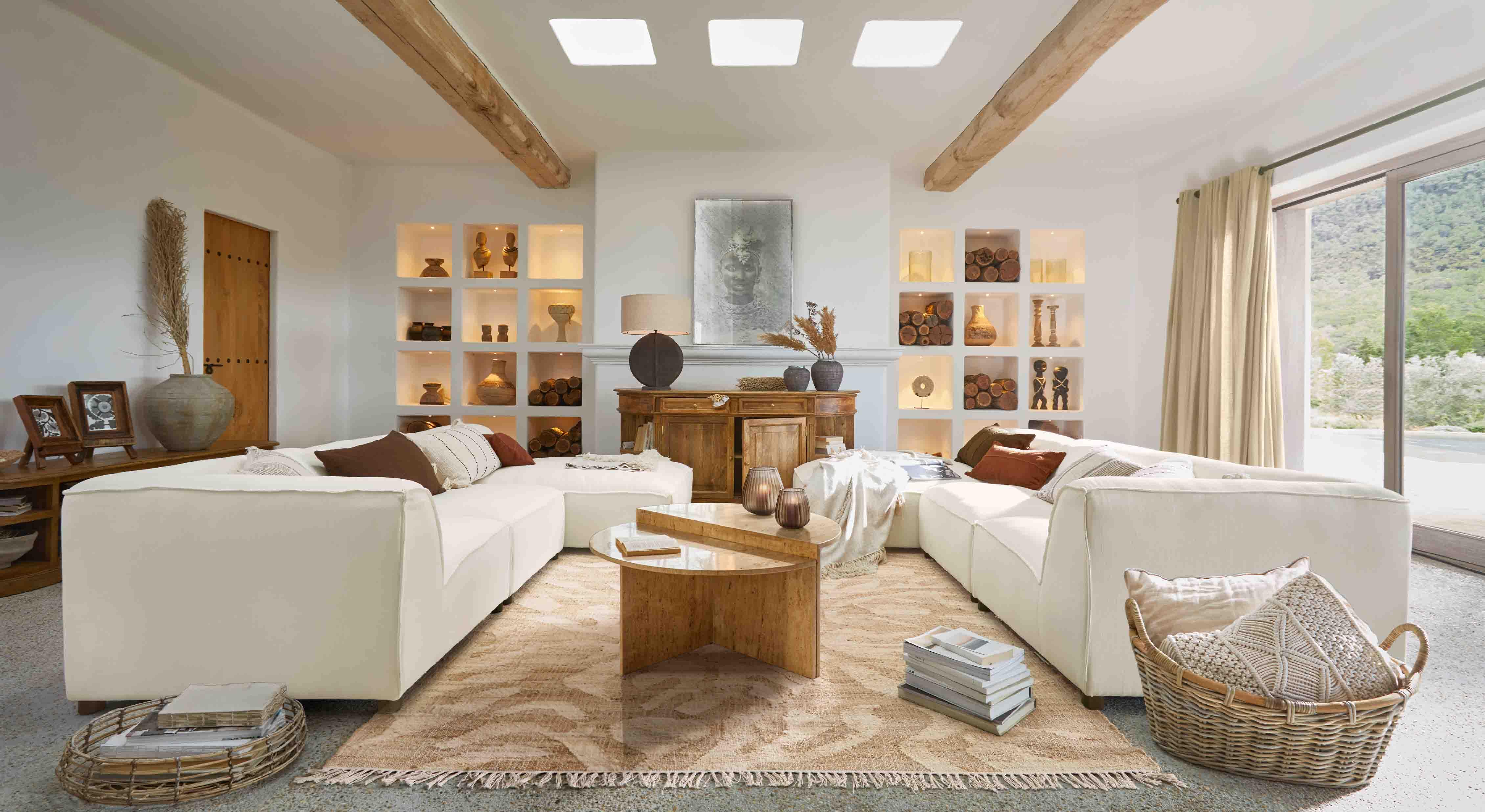 Ampio soggiorno con divano angolare bianco, tavolino in legno e decorazioni naturali calde