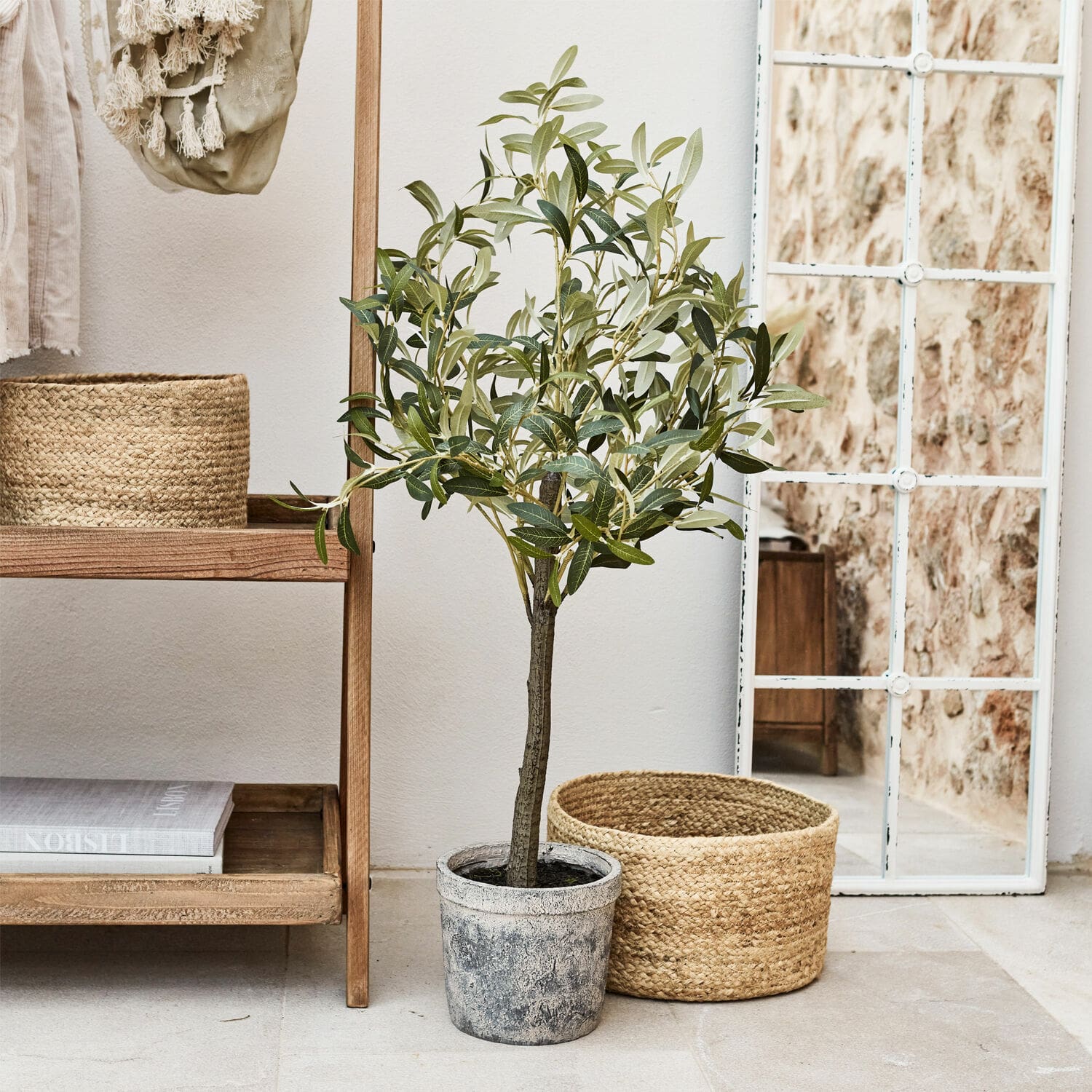 Pianta in vaso decorativa Mariuccia Albero di ulivo artificiale in vaso grigio accanto a cesta di vimini e specchio con cornice bianca