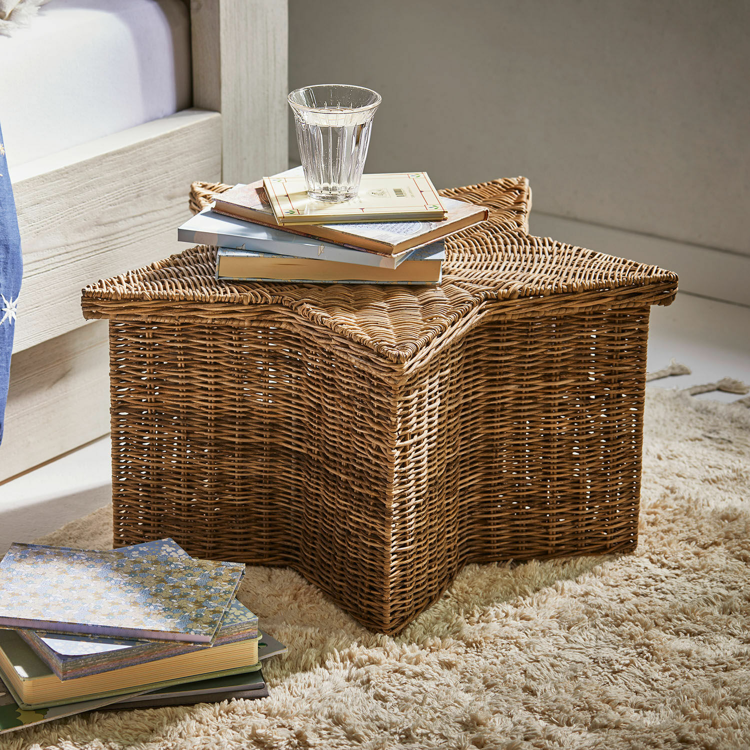Cesto Rivolina Cesto in rattan a forma di stella su tappeto con libri e bicchiere d'acqua, colore naturale
