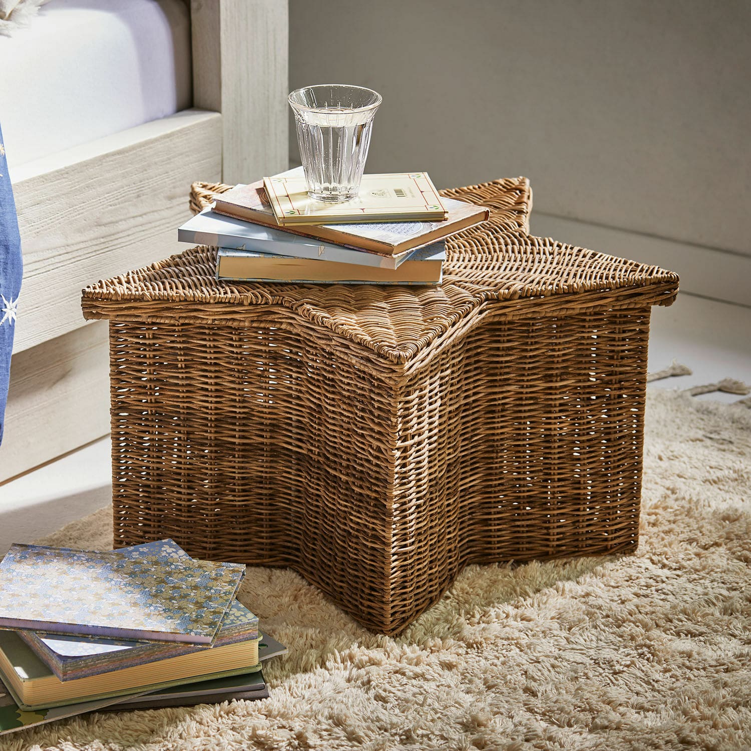 Cesto Rivolina Cesto in rattan a forma di stella su tappeto con libri e bicchiere d'acqua, colore naturale