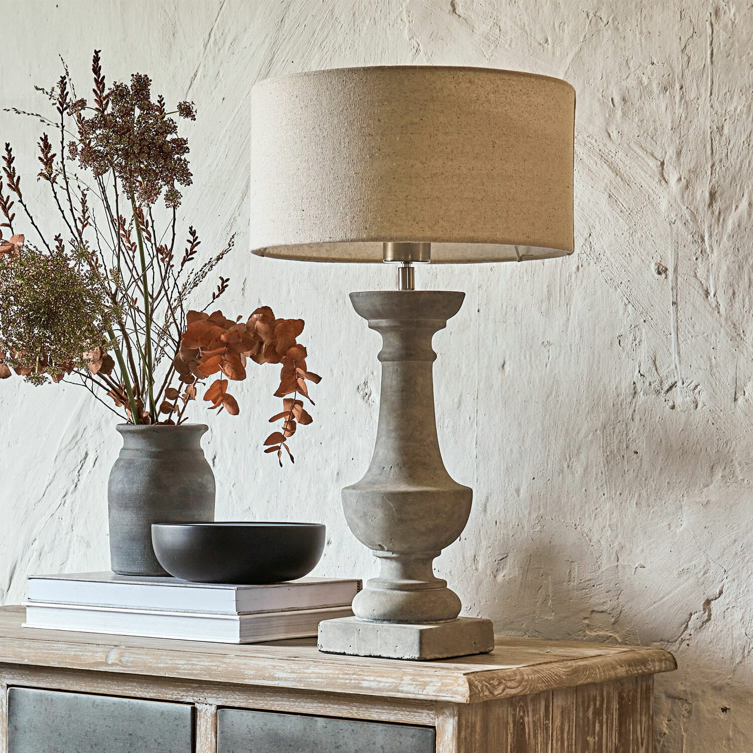 Lampada da tavolo Tifaine Lampada da tavolo in cemento con paralume beige su comò in legno con decorazioni