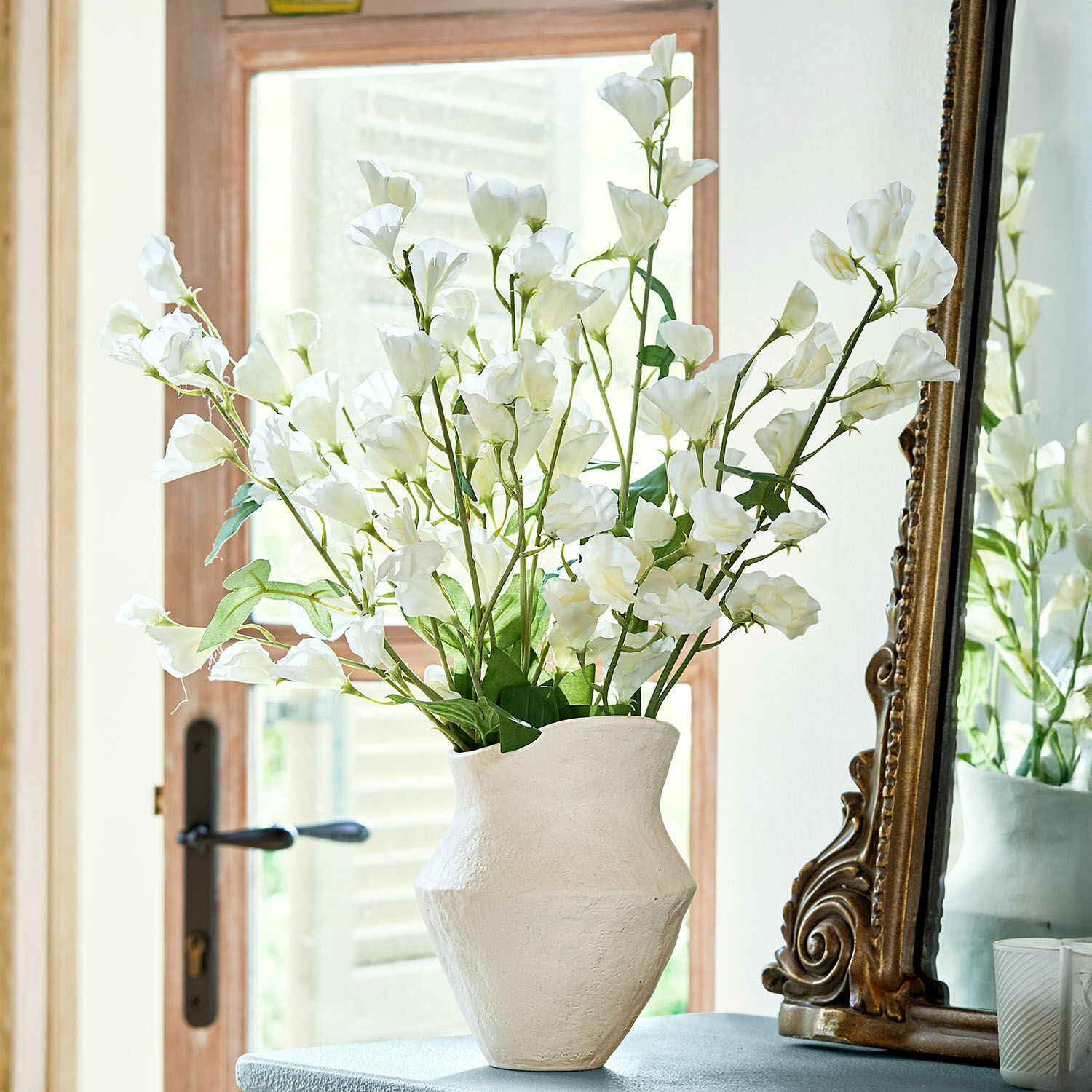 Set di 6 fiori Clavigny Vaso in ceramica bianca con fiori decorativi bianchi su tavolo accanto a uno specchio antico