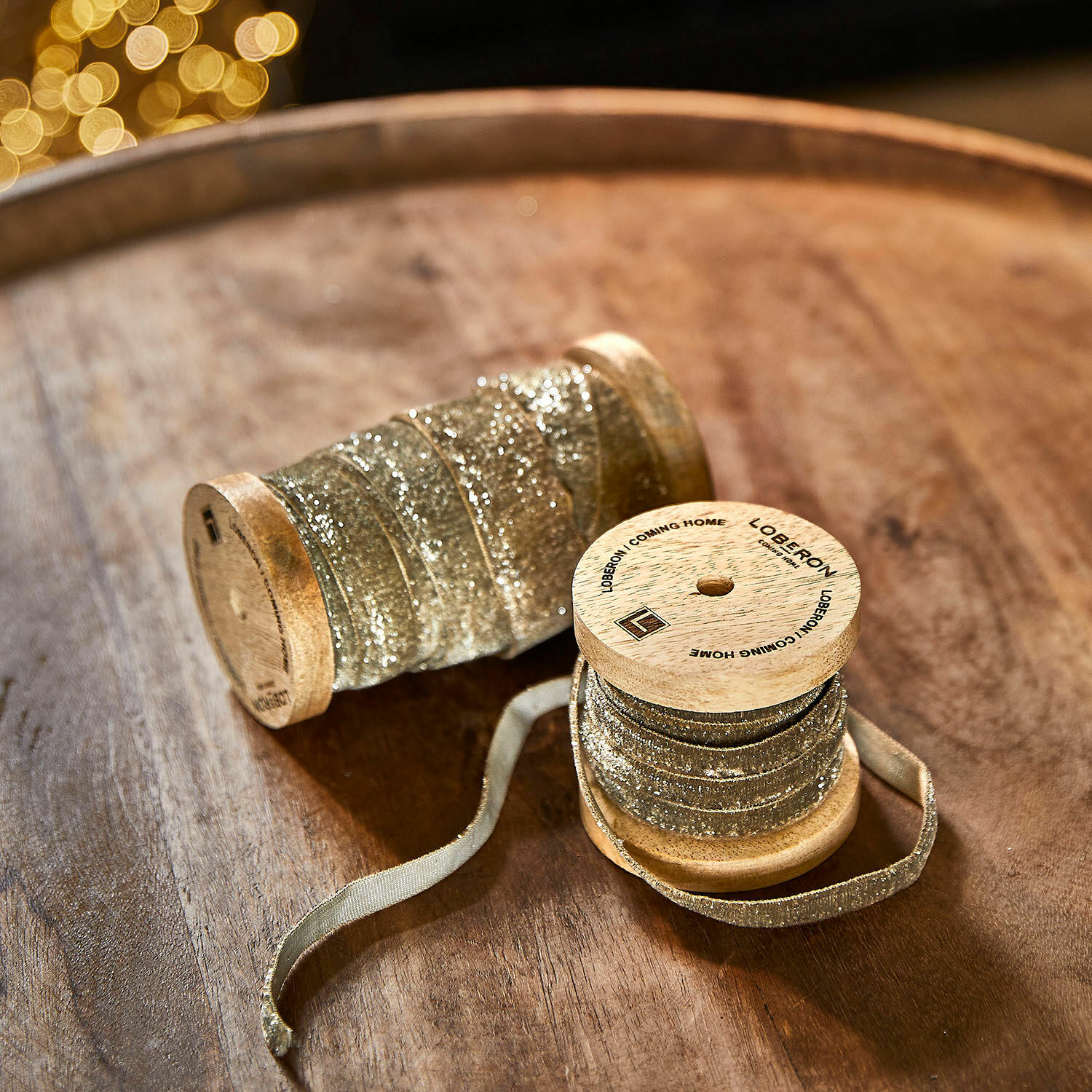 Coppia di nastri di velluto Risorio Bobine di legno con nastro dorato glitterato su tavolo in legno per decorazioni festive