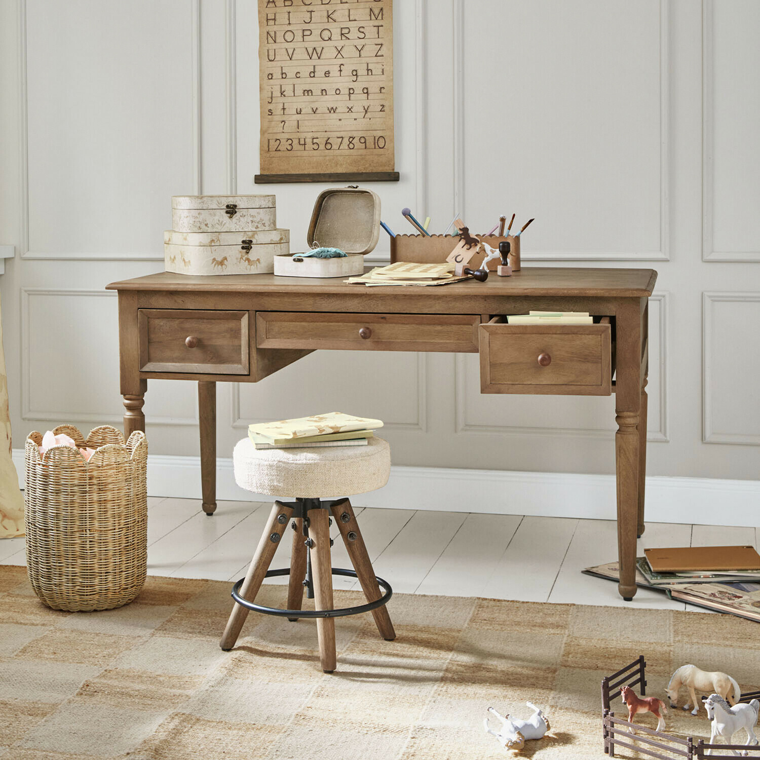 Scrivania per bambini Norleigh Scrivania in legno con tre cassetti e sgabello beige in stanza luminosa con decorazioni educative