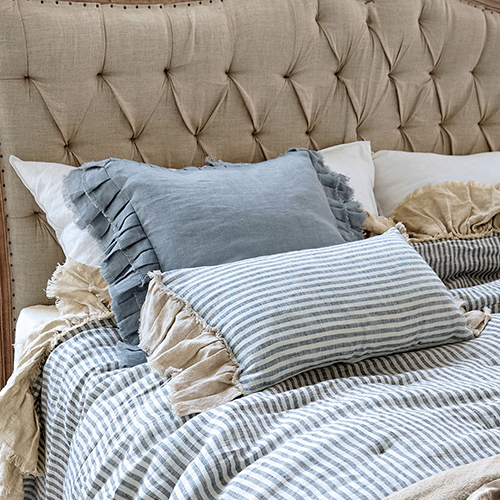 Biancheria da letto a righe in cotone con cuscini in lino su testiera imbottita beige