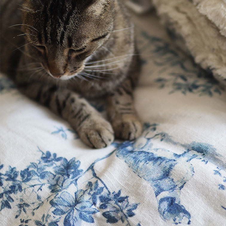 Gatto tigrato grigio su tessuto bianco con motivo floreale blu, decorazione morbida per la casa