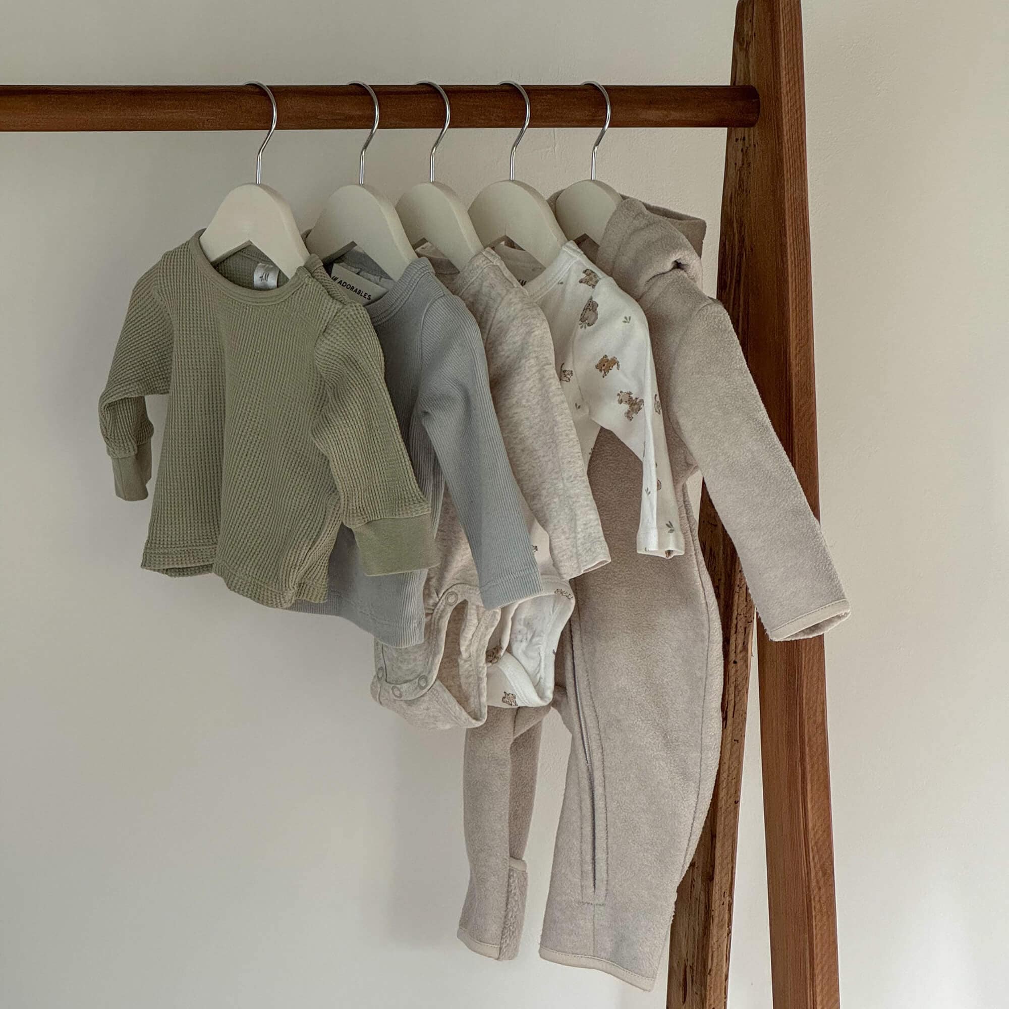Set di abbigliamento per bambini in colori neutri appesi, tessuti morbidi con motivi di orsetti