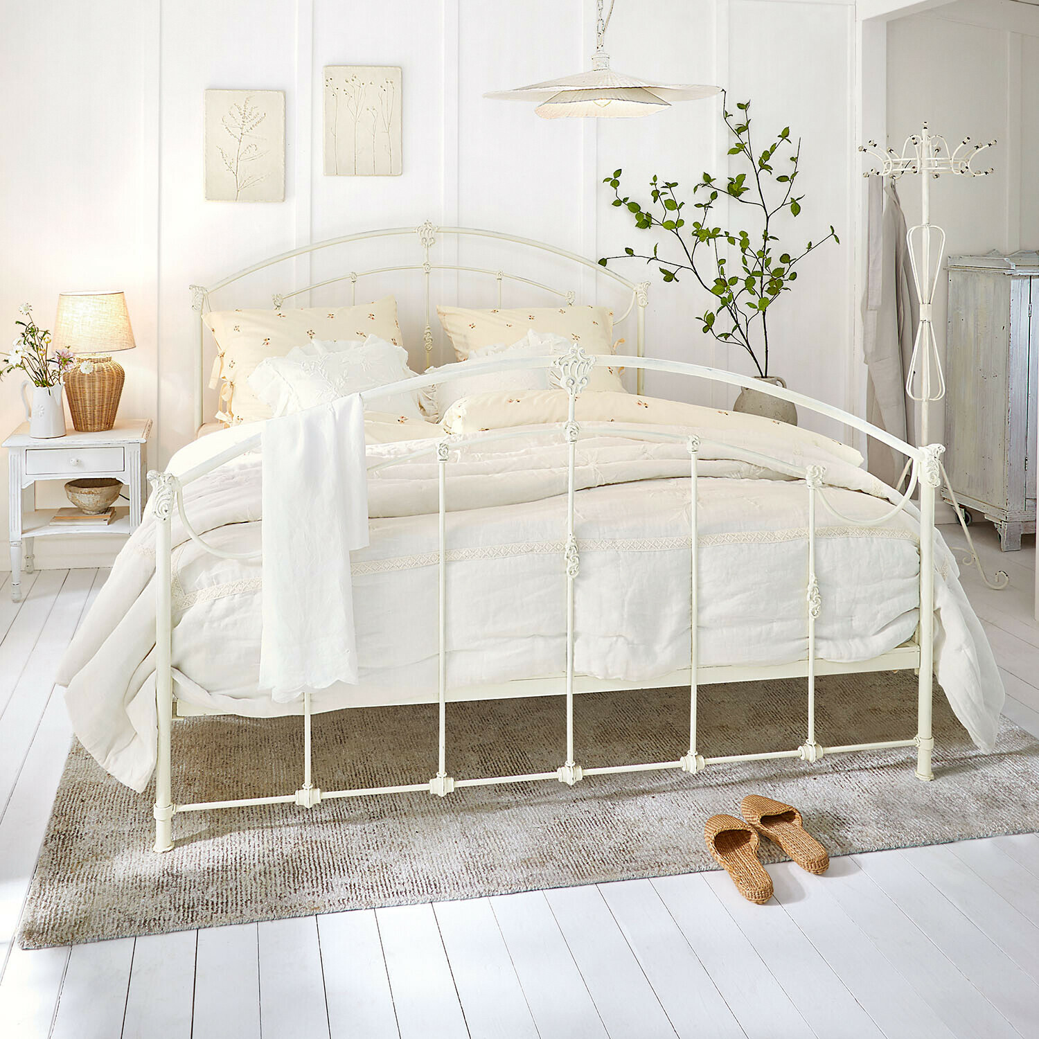 Letto Canefield Letto in metallo bianco con biancheria crema e tappeto naturale in camera luminosa