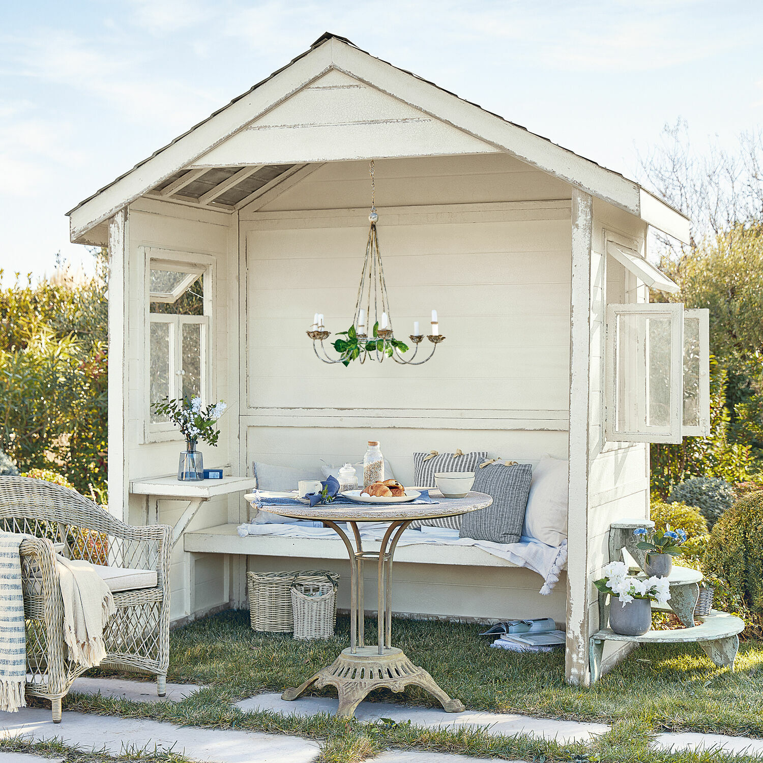 Casetta da giardino Matoury Gazebo da giardino bianco in legno con poltrona in vimini e tavolo in metallo sull'erba