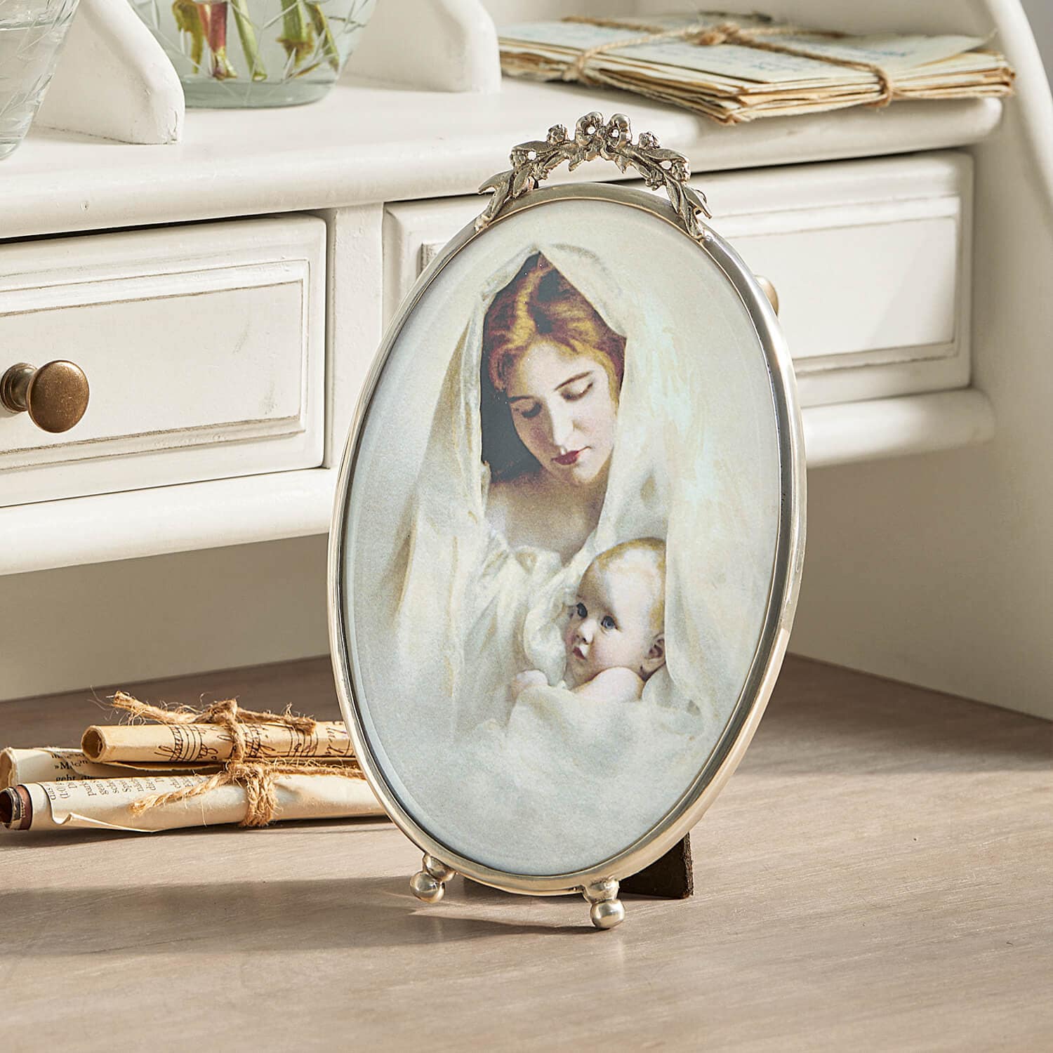 Cornice ovale in metallo con decorazioni e immagine di madre con bambino in tessuto bianco