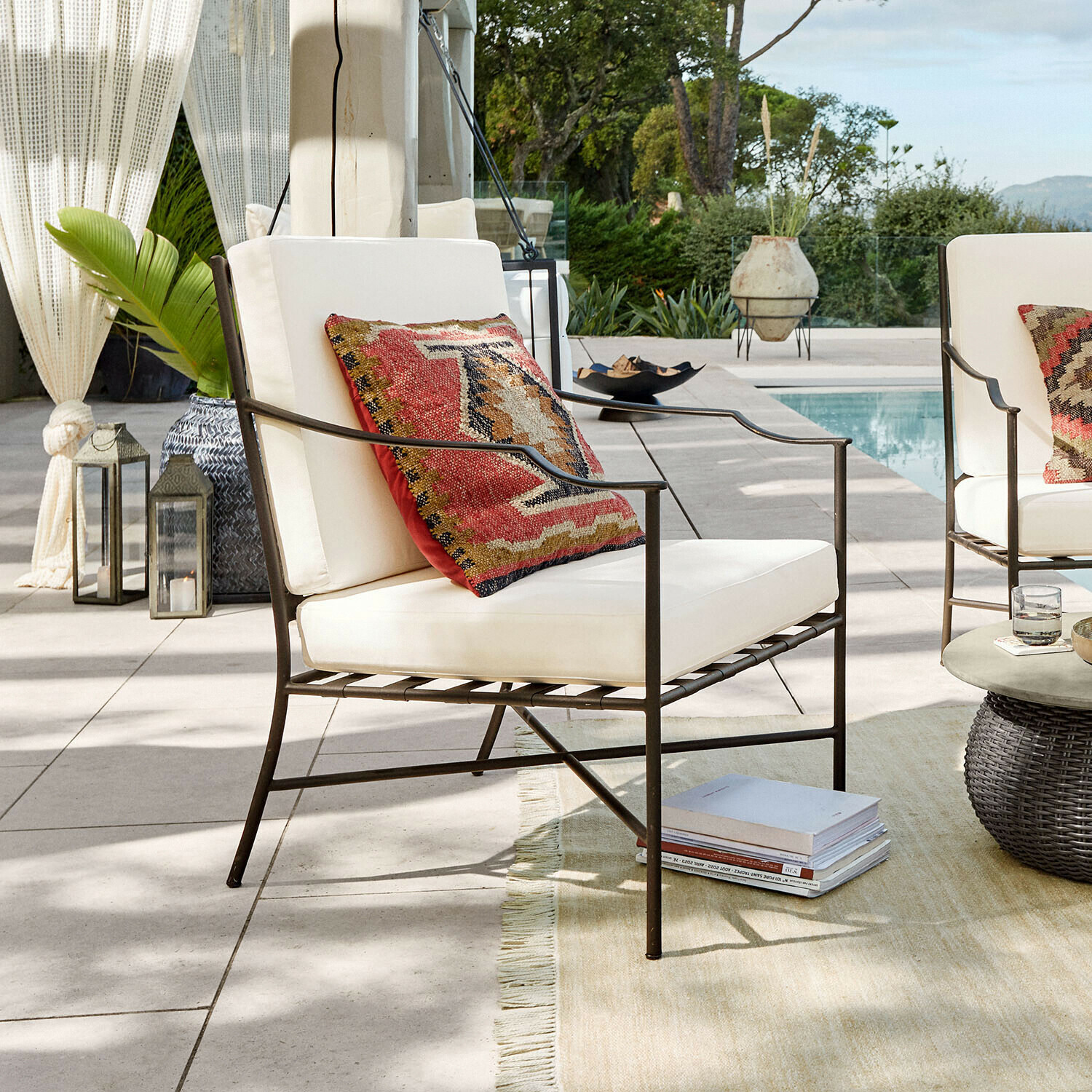 Poltrona Vexford Poltrona da giardino in metallo con cuscini crema e cuscino decorativo colorato vicino alla piscina