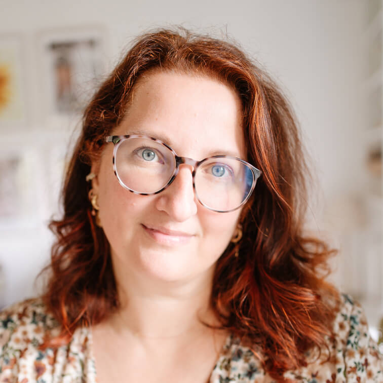 Ritratto di donna con capelli rossi e occhiali in interno luminoso sfocato
