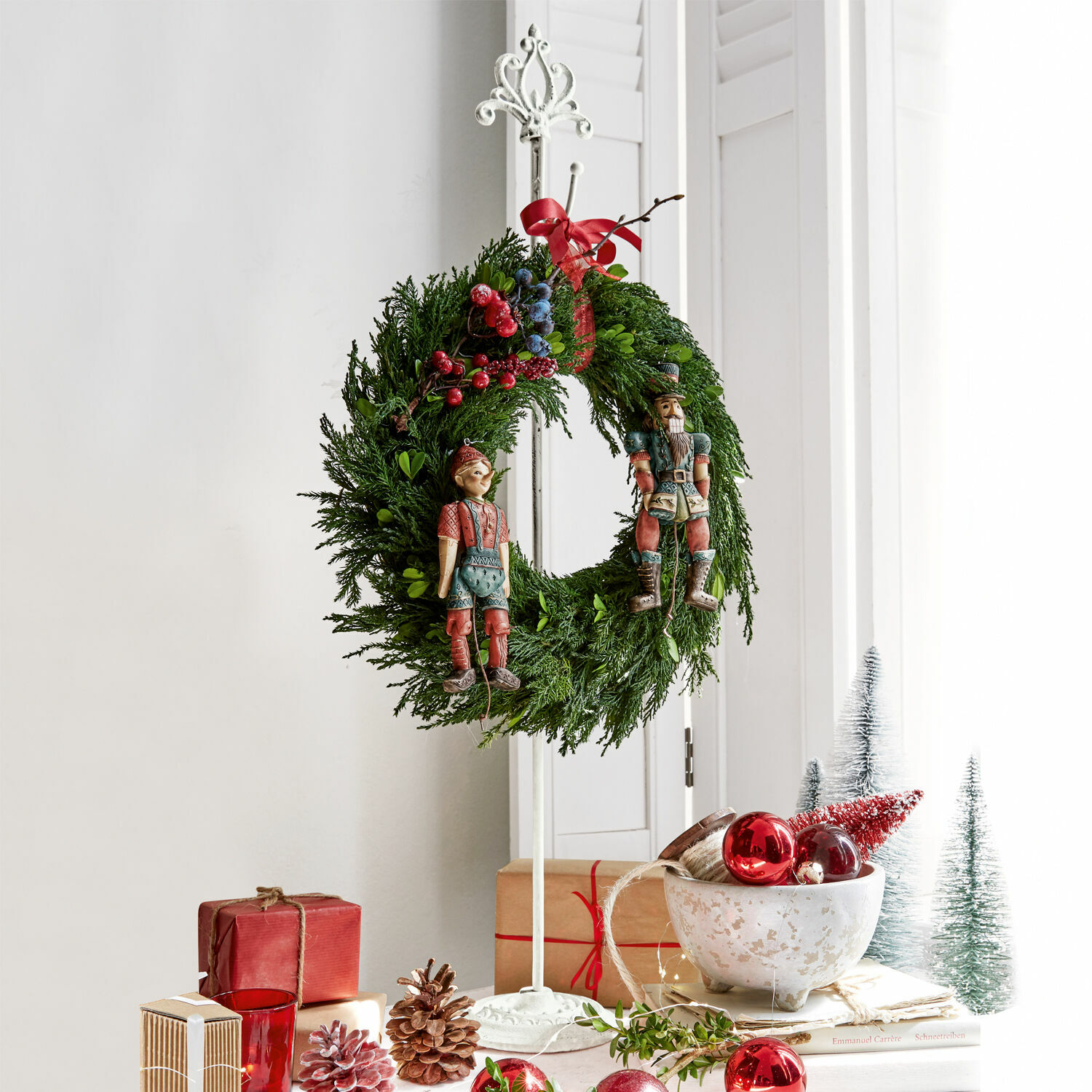 Supporto per ghirlanda Irulan Corona natalizia di rami verdi con bacche rosse e blu e figure in legno su supporto bianco
