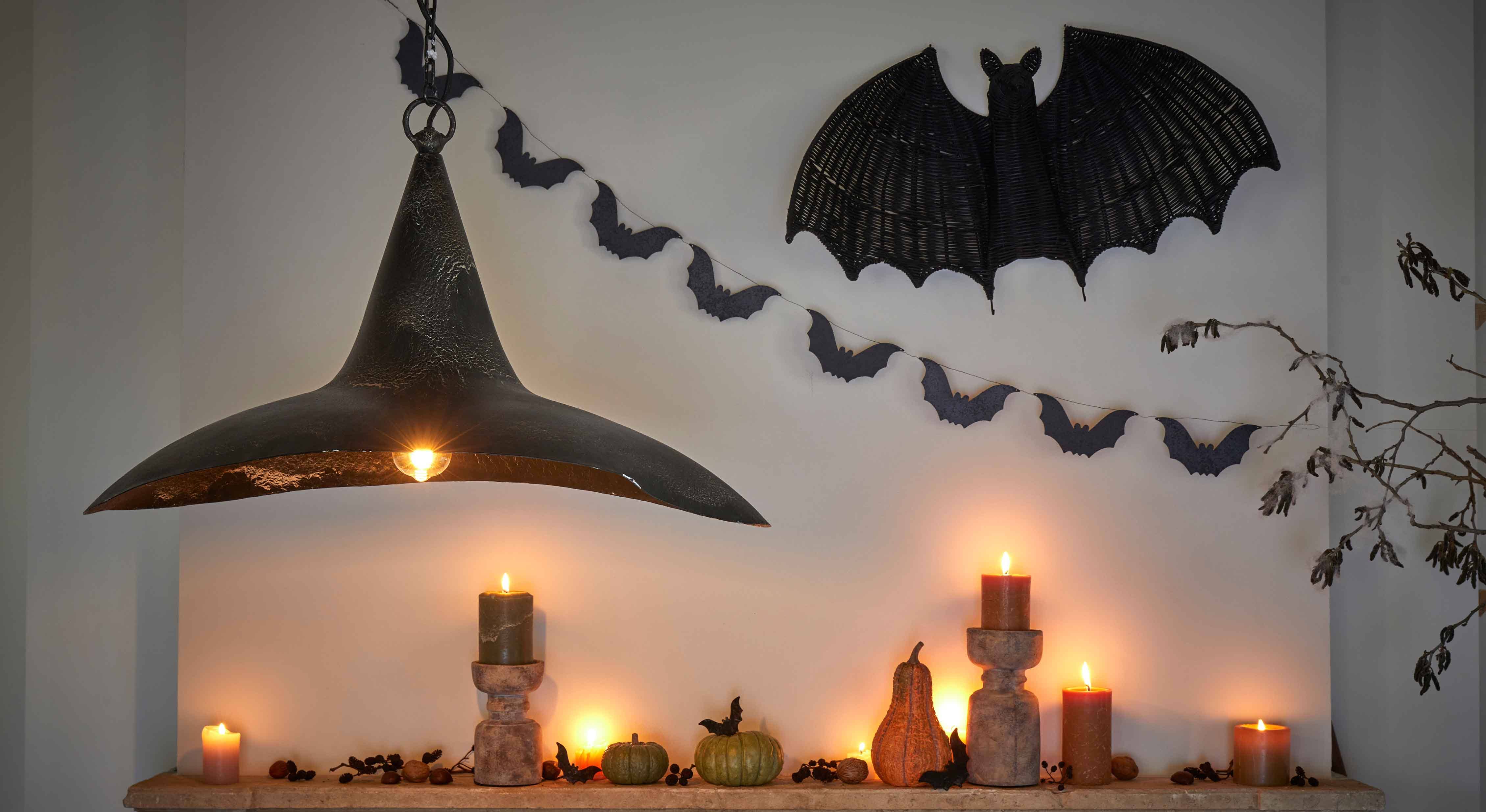 Decorazione di Halloween con candele nere, zucche e lampada in metallo nero su parete con pipistrelli