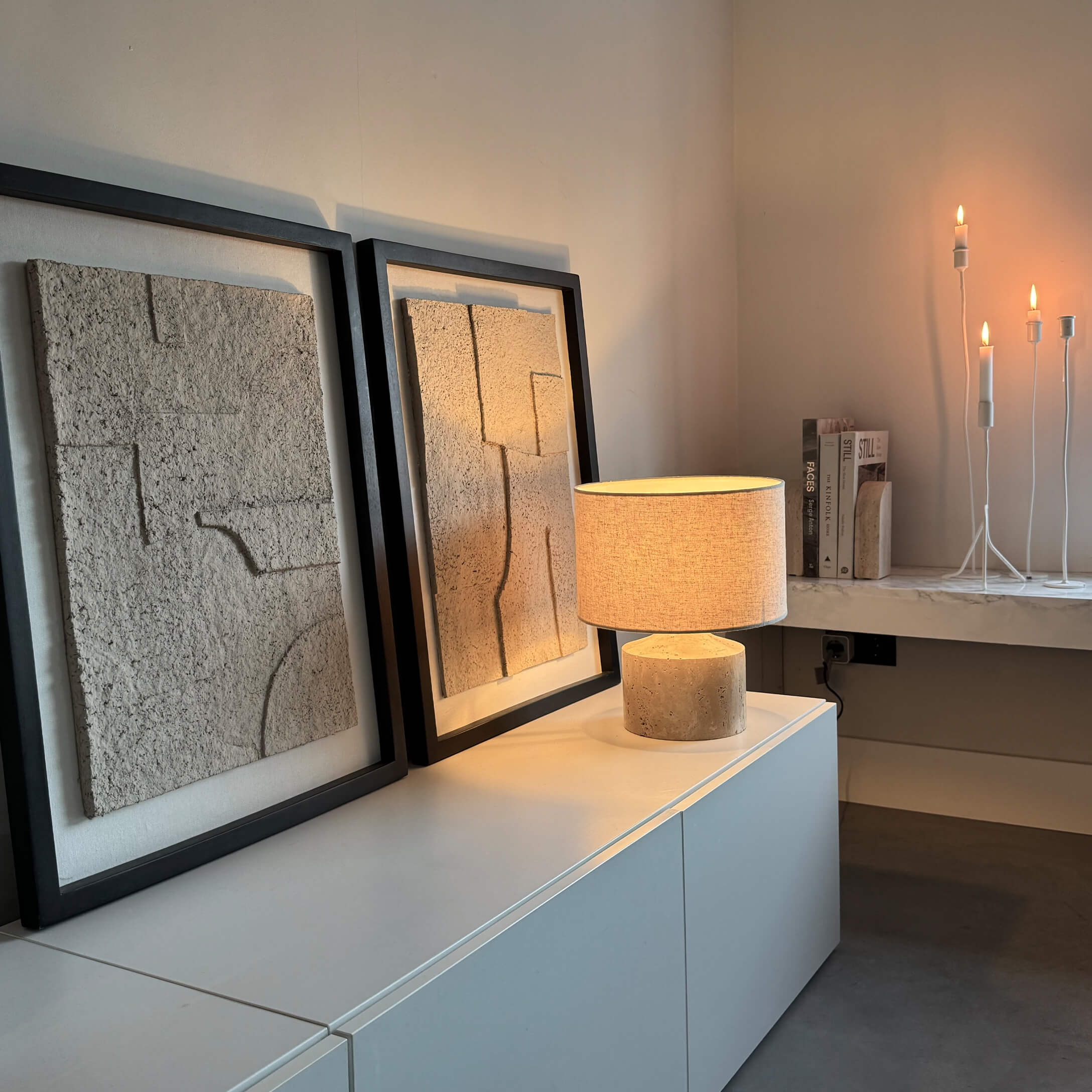 Lampada da tavolo moderna con paralume beige e base in pietra su mobile bianco con decorazione murale