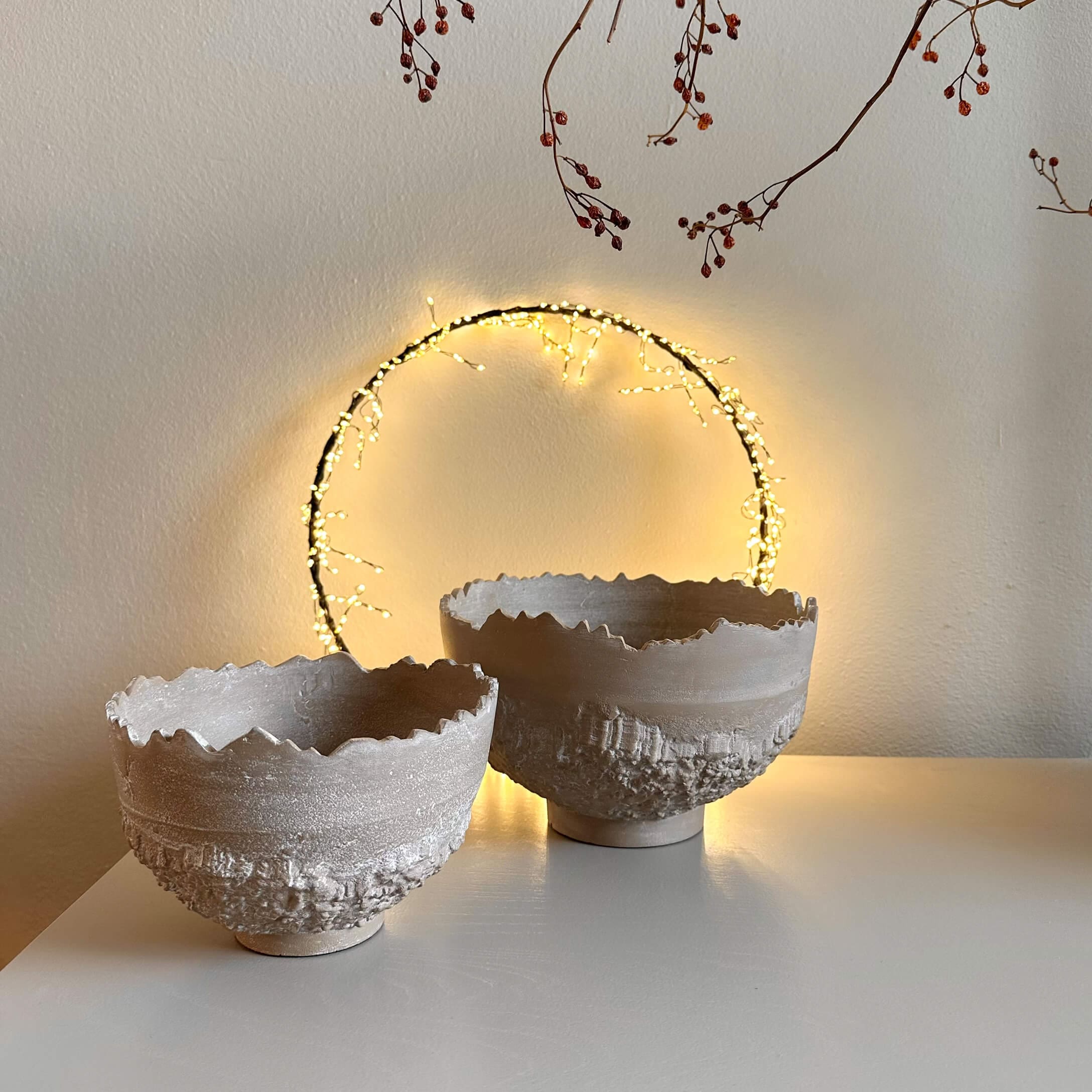 Due ciotole decorative in ceramica beige con texture ruvida e bordo irregolare su tavolo bianco