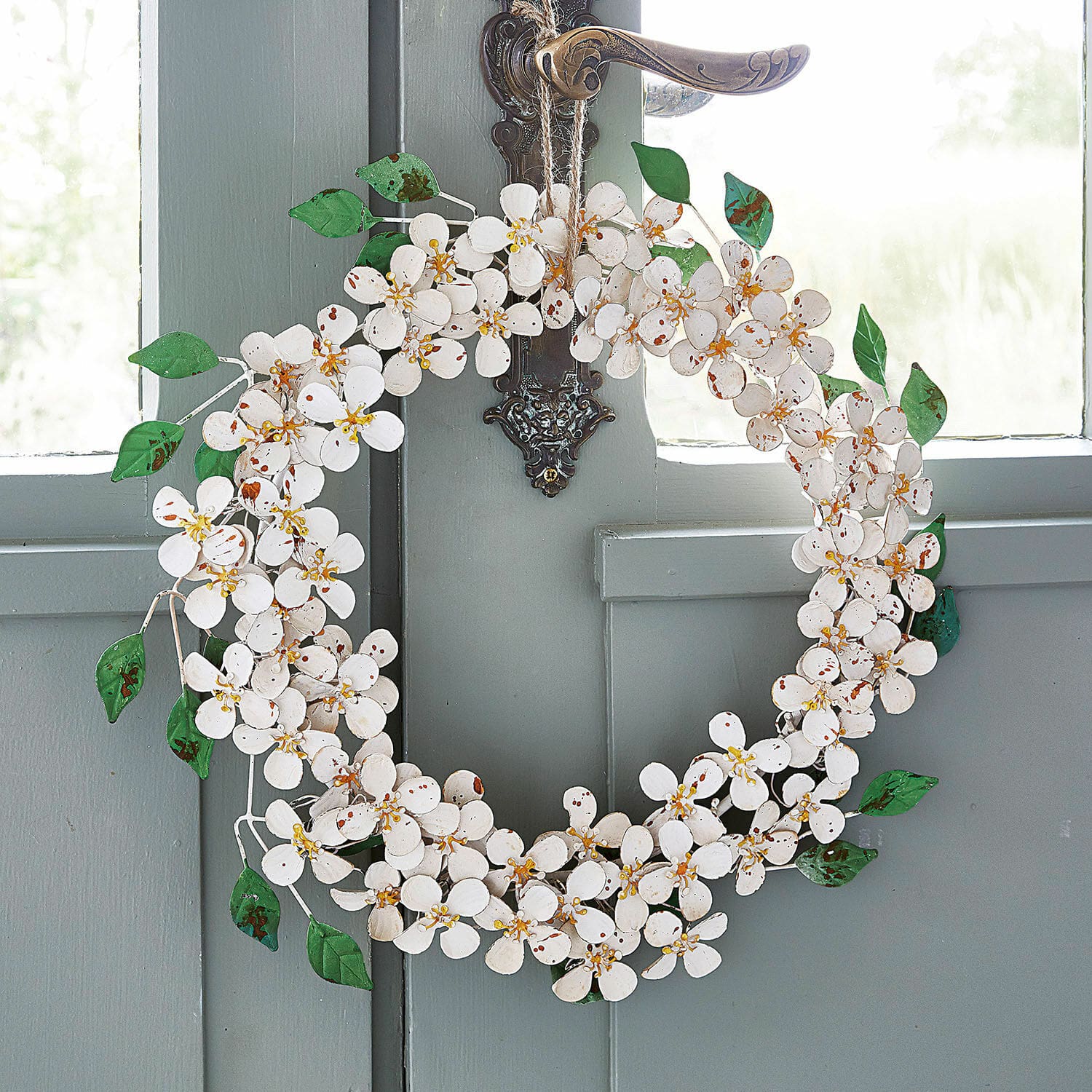 Ghirlanda Loanne Corona decorativa in metallo bianco con fiori e foglie verdi appesa a porta grigia