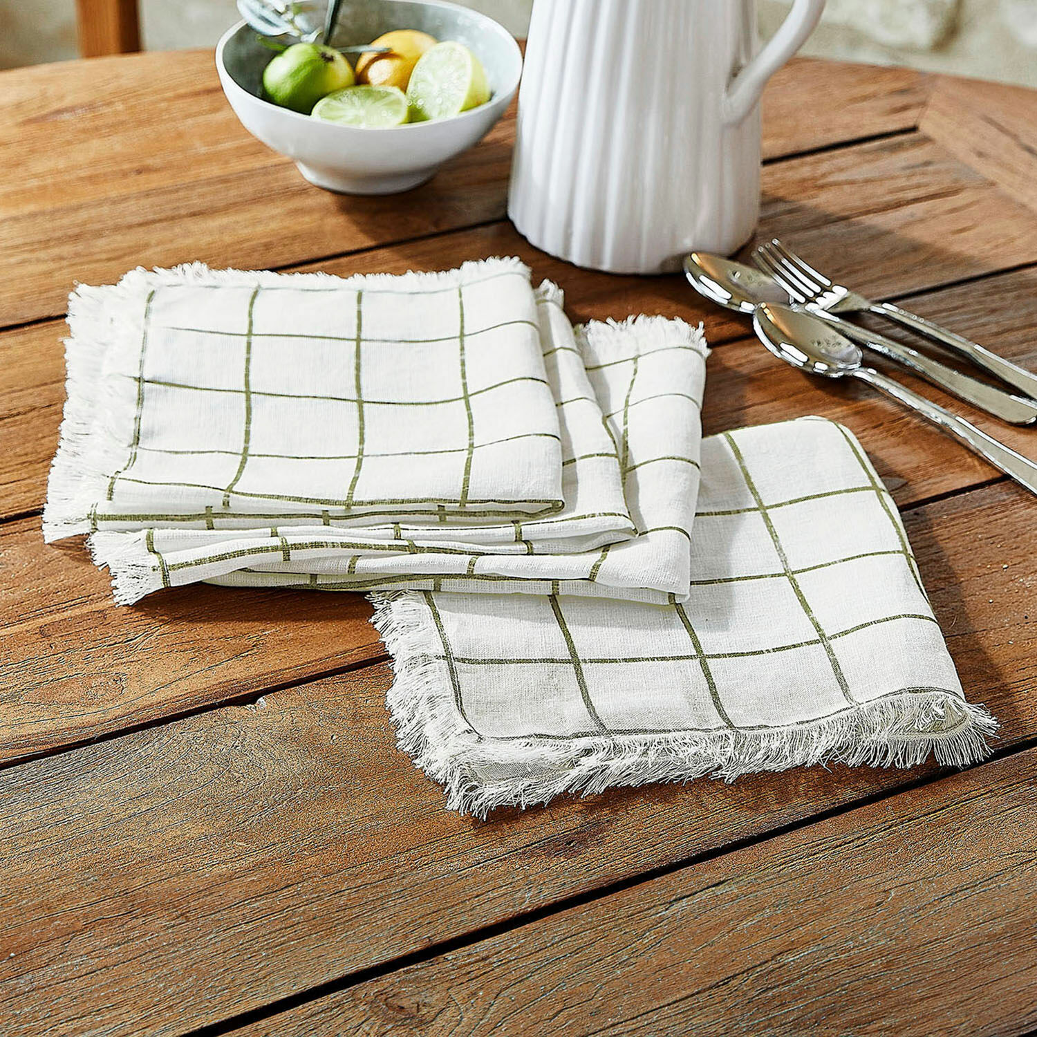 Set di 4 tovaglioli Klivento Tovaglioli in lino bianco con motivo a quadri verdi e frange su tavolo in legno per decorazione