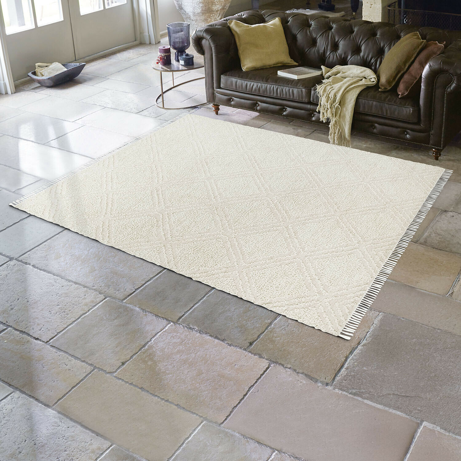 Tappeto per interni ed esterni Bruand Tappeto beige con motivo geometrico su pavimento in pietra in soggiorno con divano in pelle marrone scuro