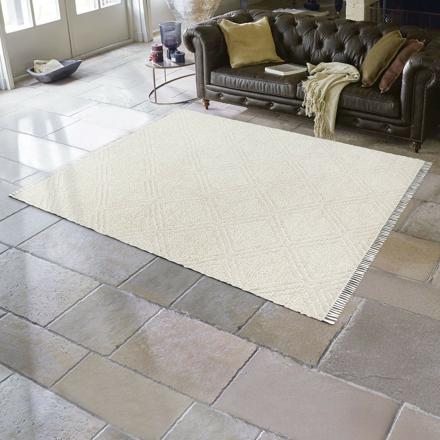 Tappeto per interni ed esterni Bruand Tappeto beige con motivo geometrico su pavimento in pietra in soggiorno con divano in pelle marrone scuro