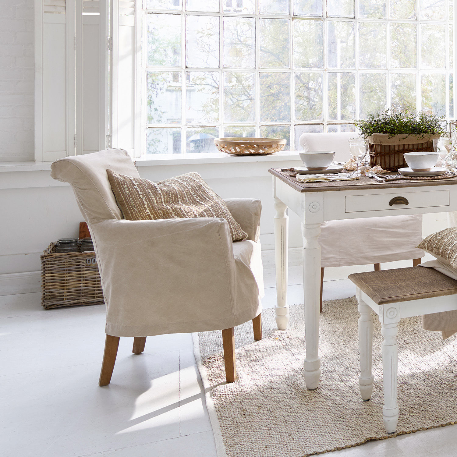 Sedia Amherst Poltrona beige in tessuto con gambe in legno in una sala da pranzo luminosa e naturale