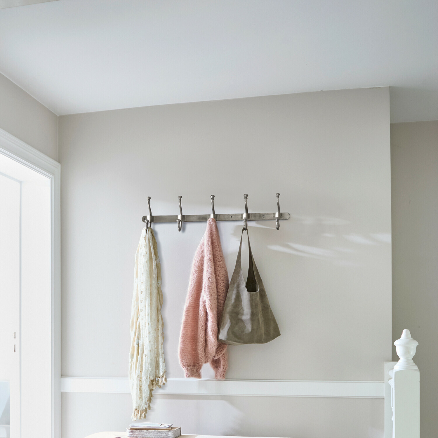 Attaccapanni da parete in metallo con cinque ganci con maglione rosa, sciarpa e borsa appesi