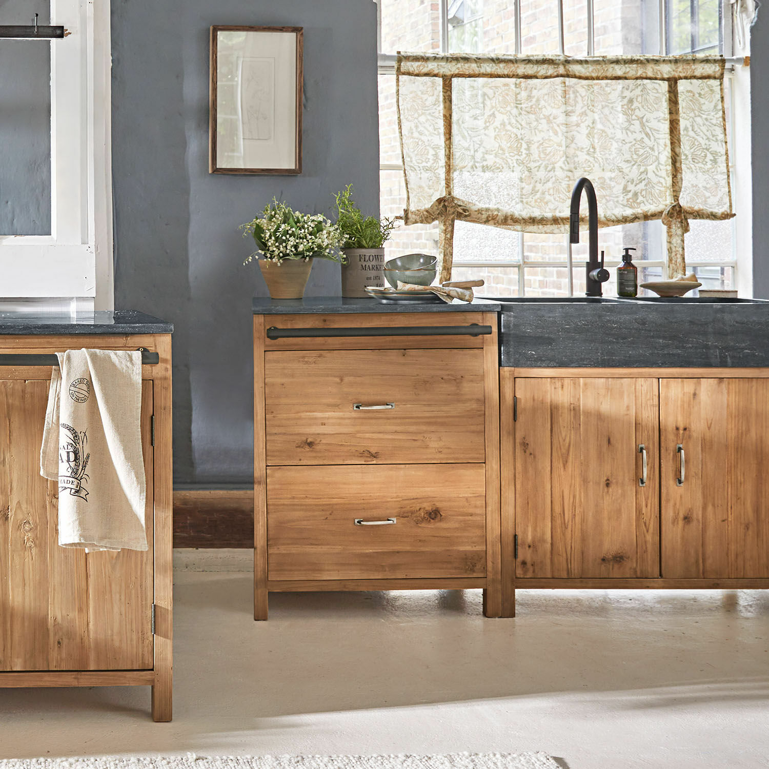 Base da cucina Sunnybrook Cucina con mobili in legno e piano nero, decorazioni vegetali e tende con motivo floreale