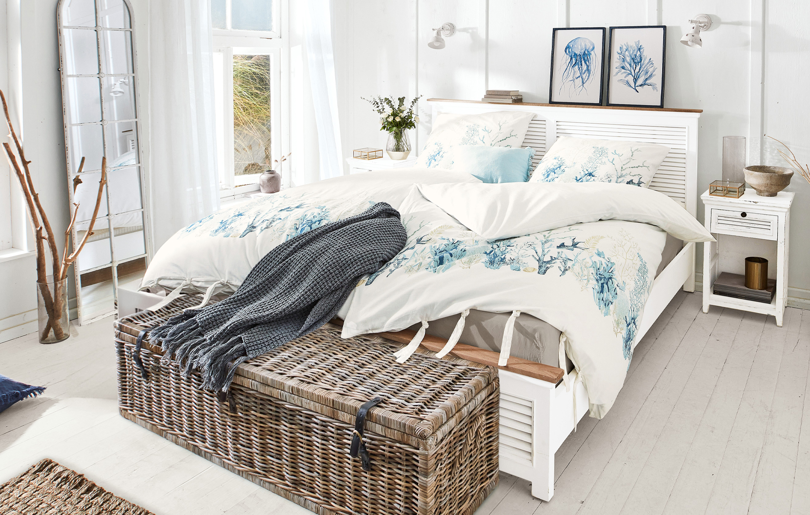 Camera da letto in stile marittimo con letto bianco e biancheria da letto con motivi marini blu