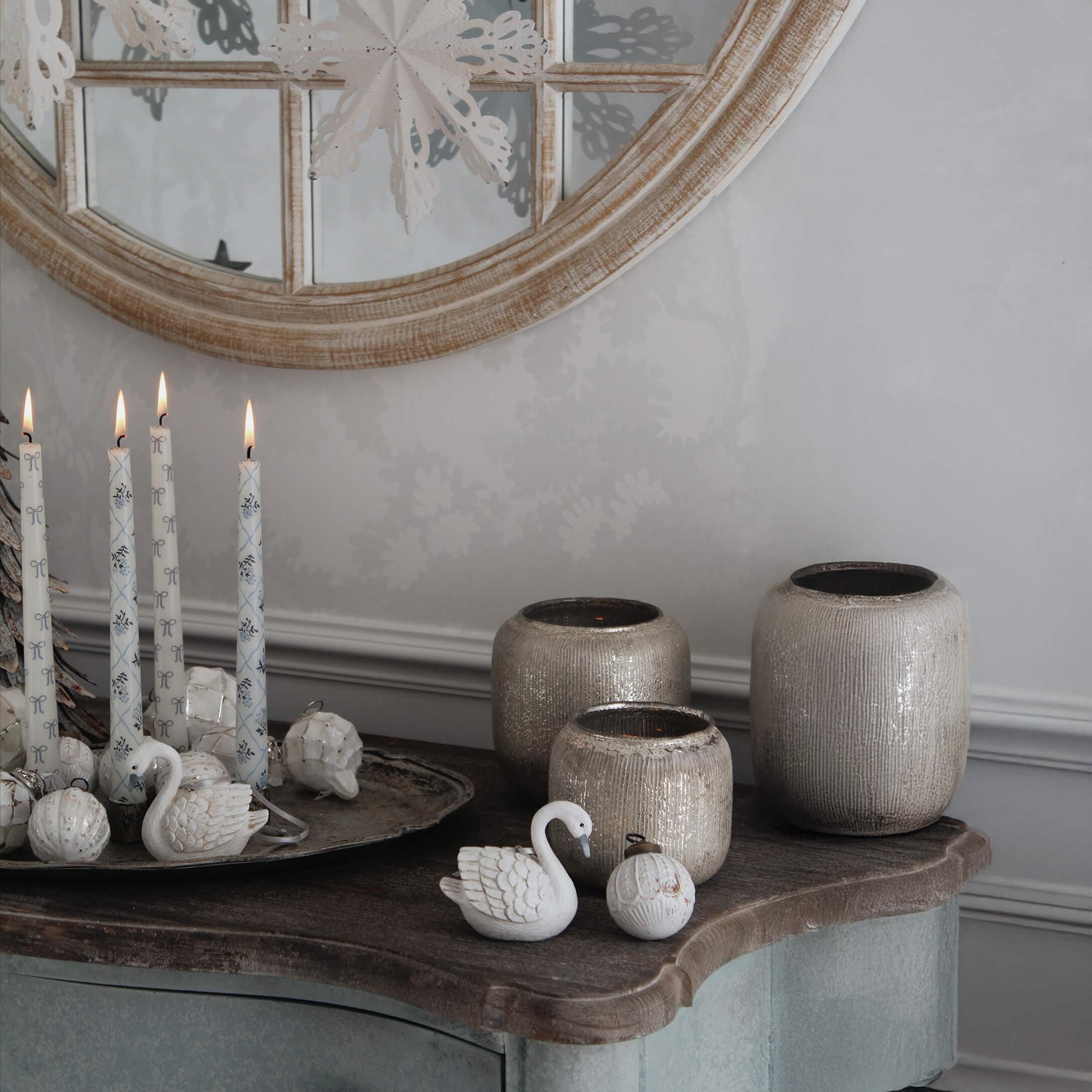 Candele bianche decorative e vasi in ceramica beige su tavolo in legno con specchio rotondo