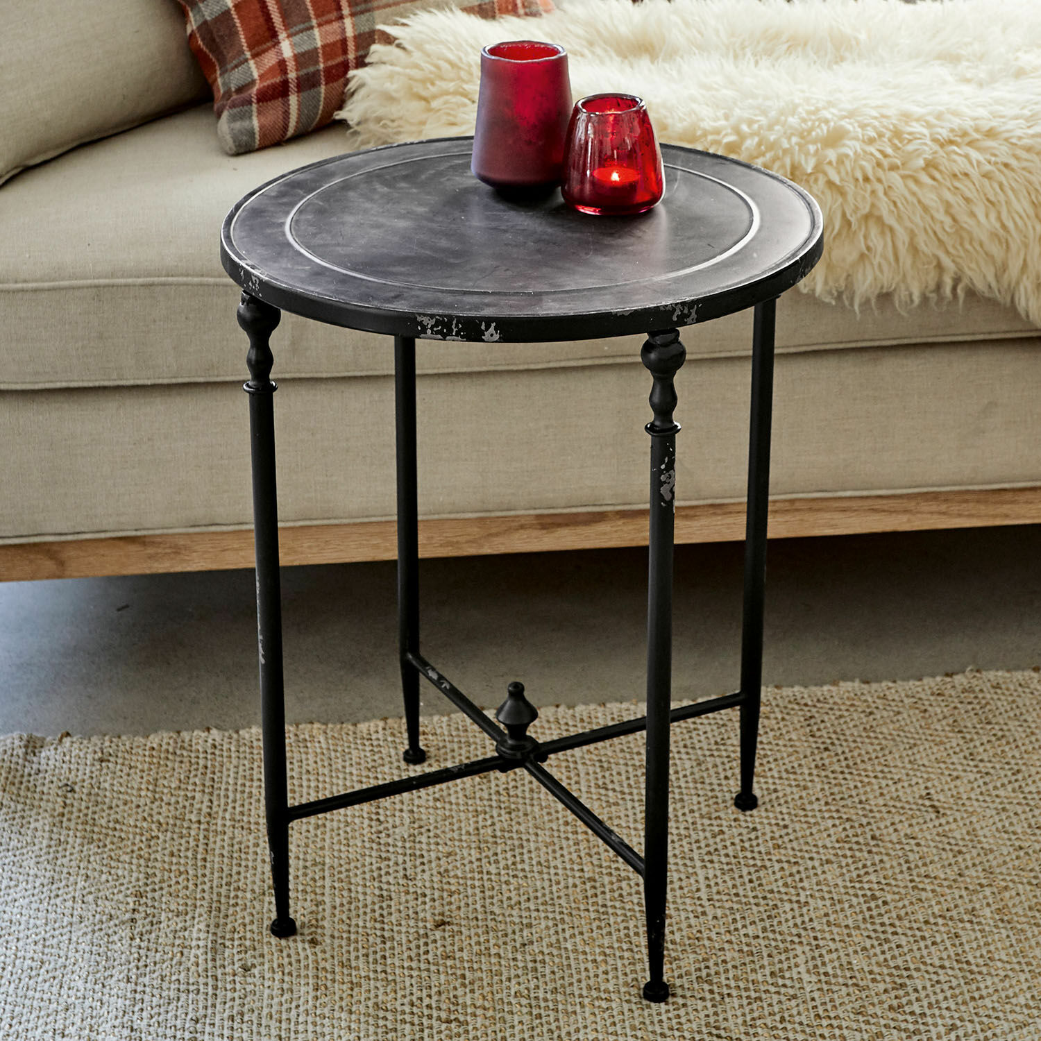 Tavolino di complemento Danbury Tavolino rotondo in metallo nero con gambe decorative su tappeto beige in soggiorno