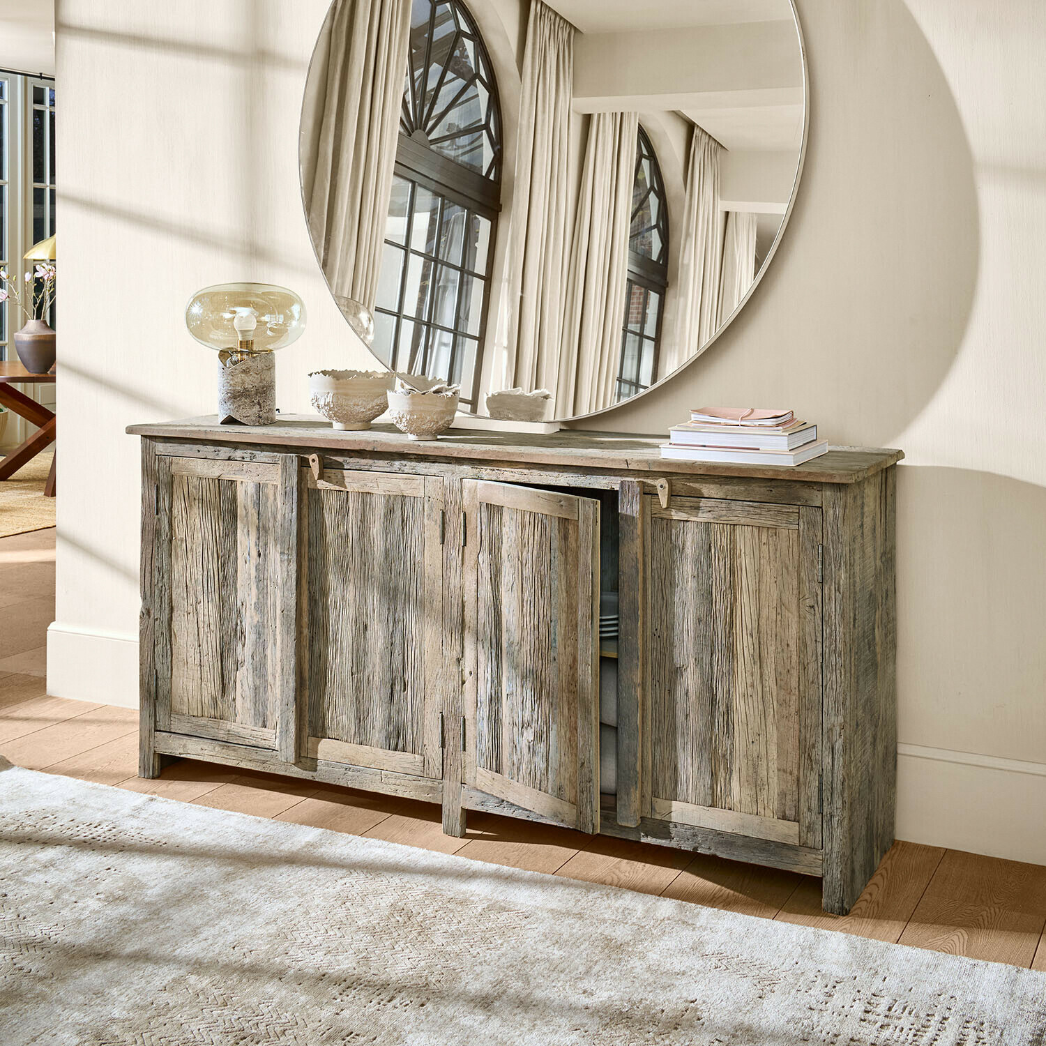 Credenza rustica in legno grigio con quattro ante e grande specchio rotondo decorativo a parete