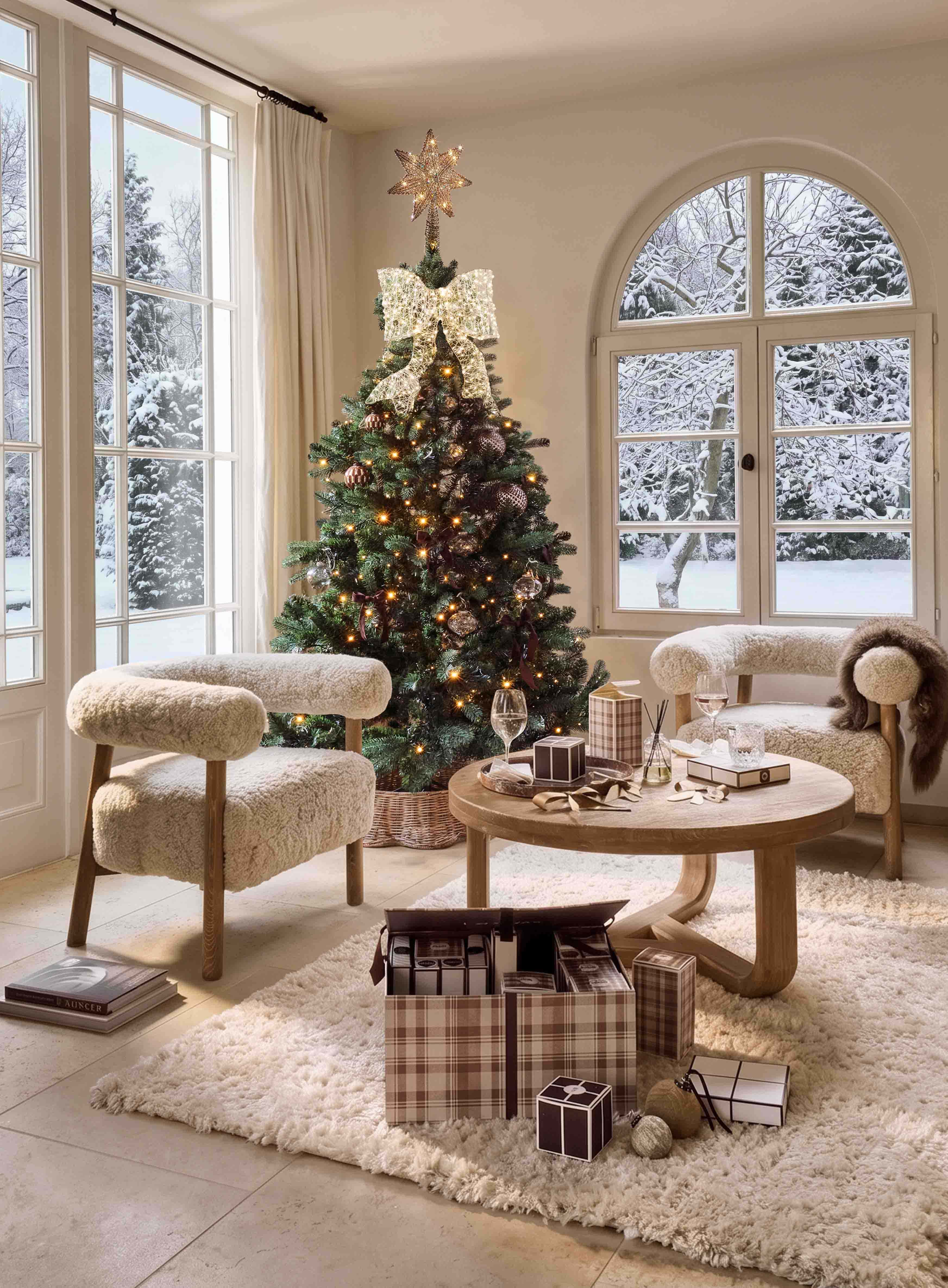 Albero di Natale decorato con stella luminosa e grande fiocco in soggiorno accogliente con vista su giardino innevato