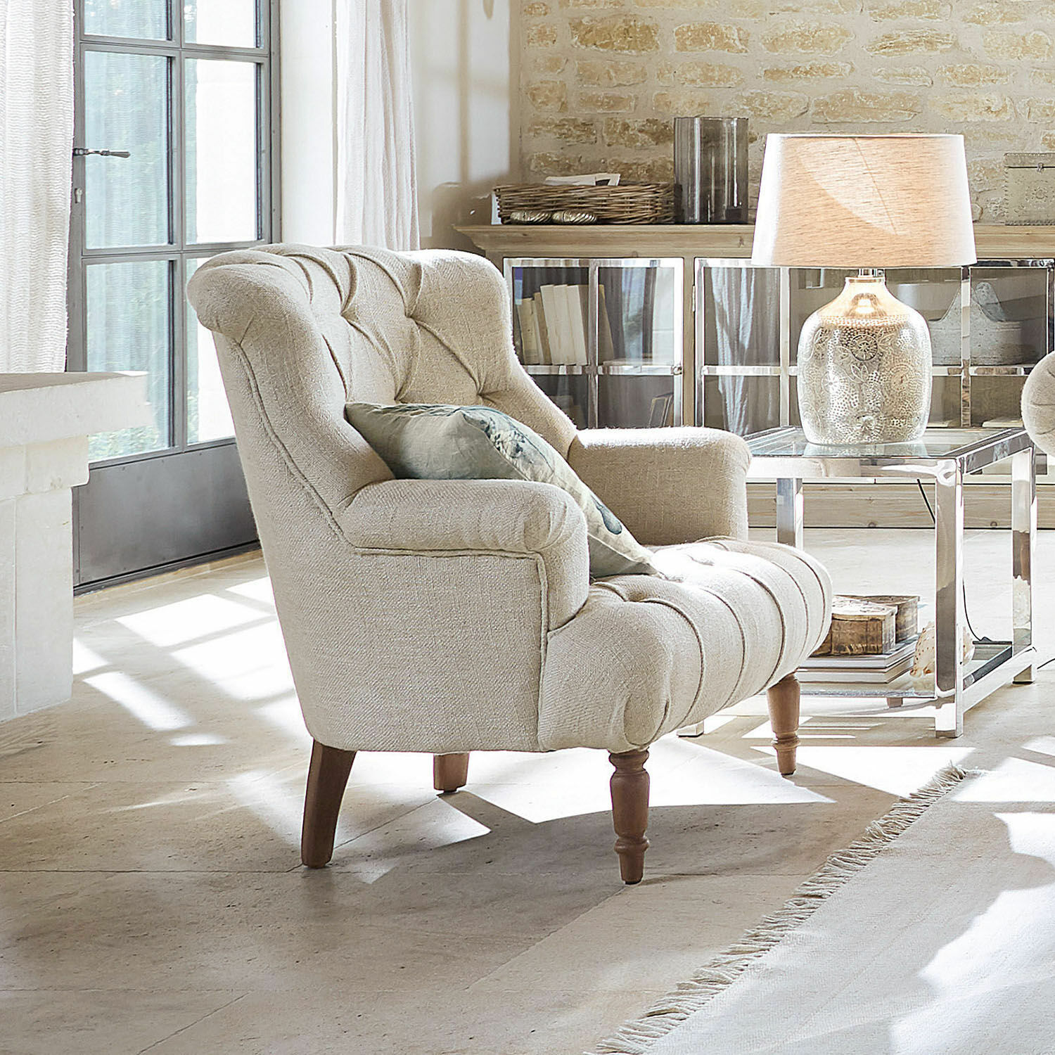 Poltrona Parranquet Poltrona beige imbottita con gambe in legno in soggiorno luminoso con lampada e tavolino