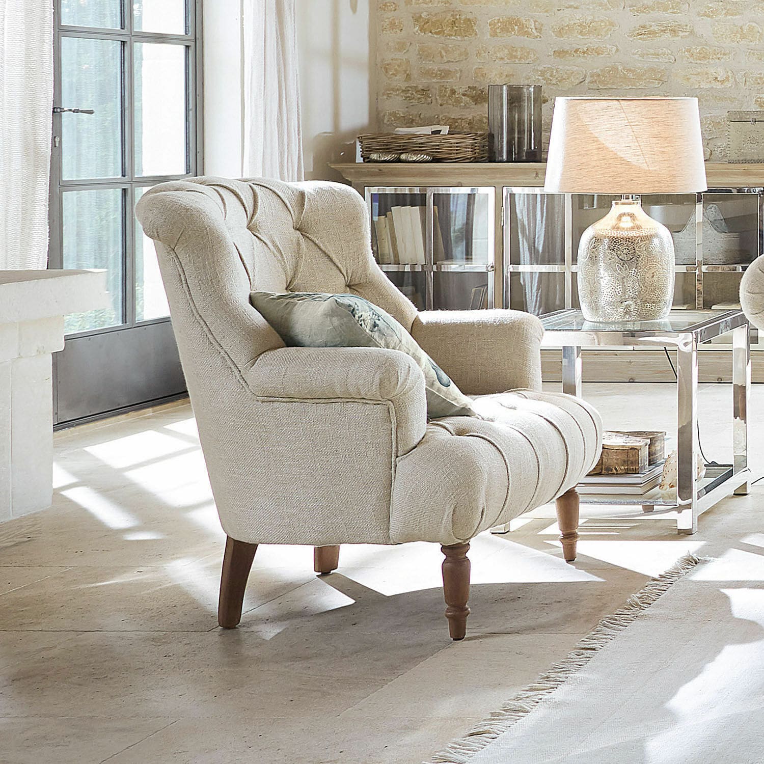 Poltrona Parranquet Poltrona beige imbottita con gambe in legno in soggiorno luminoso con lampada e tavolino