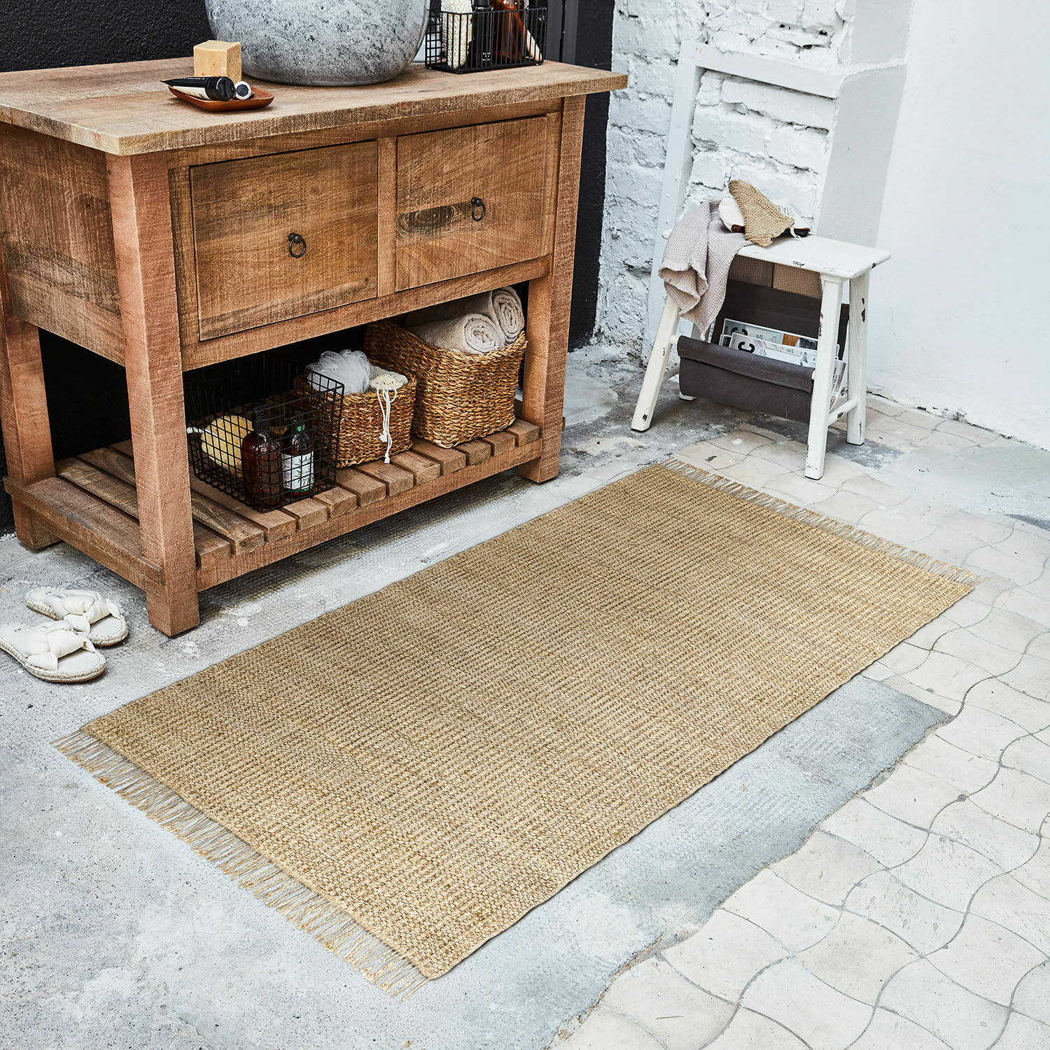 Passatoia Hermitage Tappeto naturale in juta beige sul pavimento accanto a una cassettiera in legno e uno sgabello bianco
