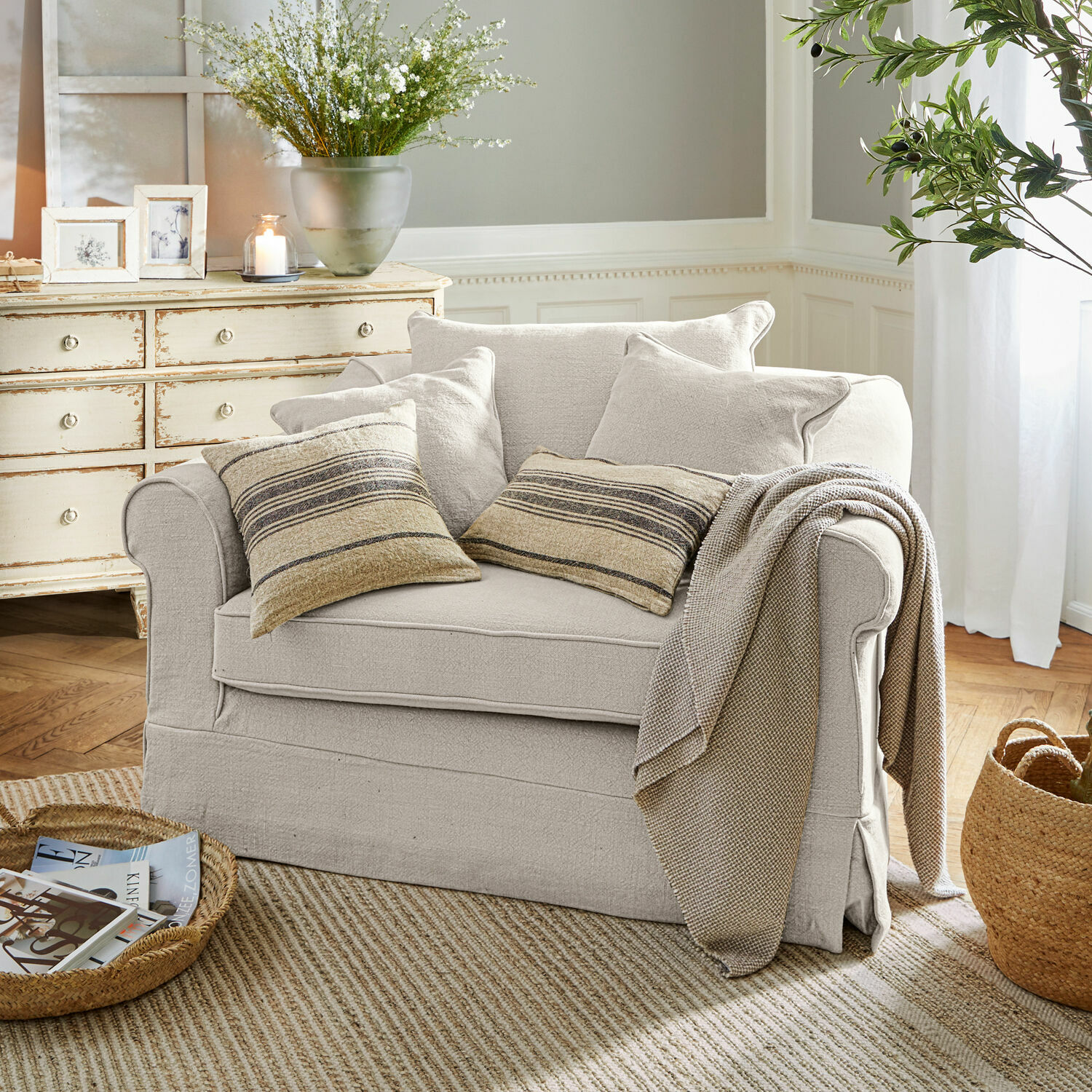 Poltrona Folsom Divano beige in tessuto con cuscini a righe e coperta in soggiorno accogliente con tappeto naturale