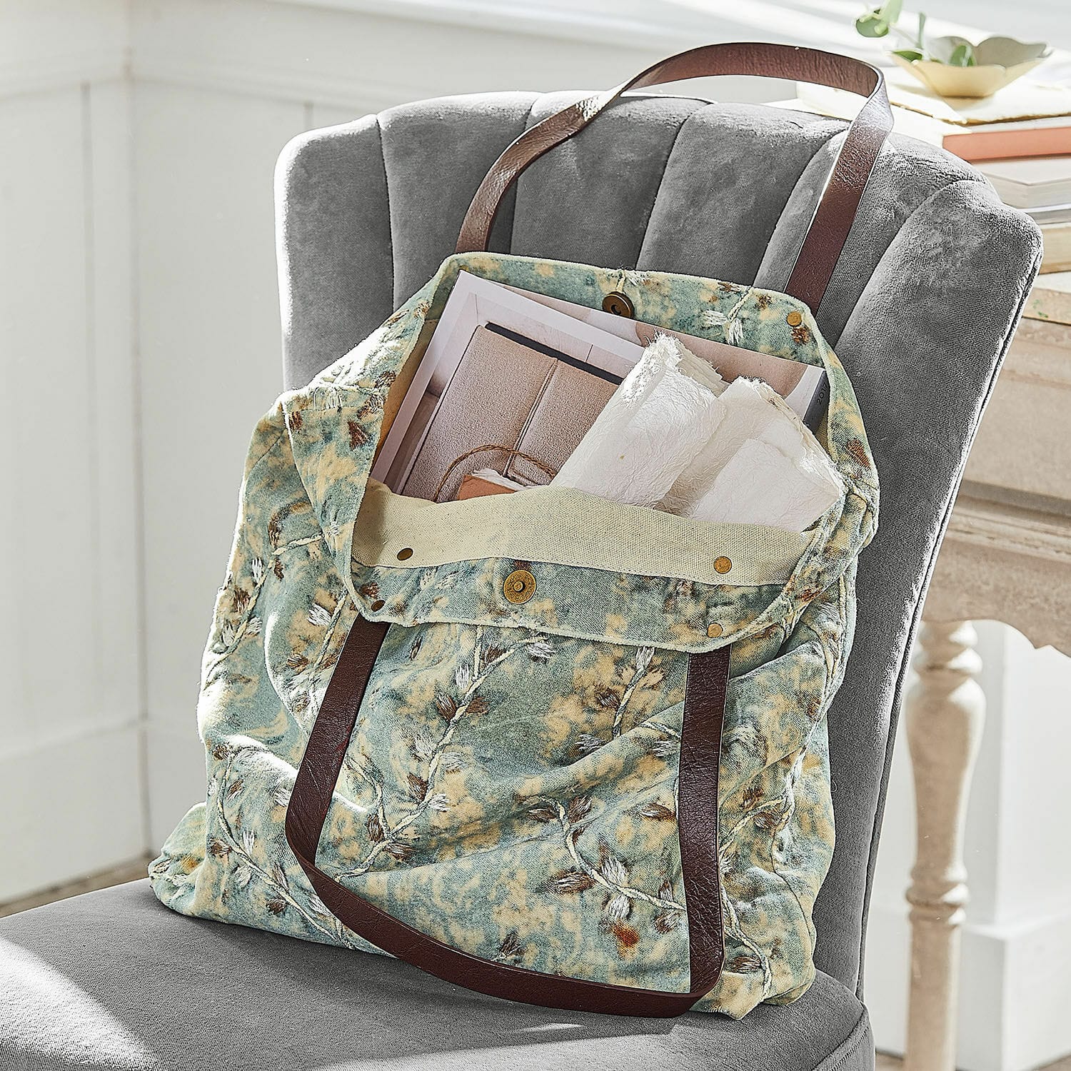 Borsa LaRoux Borsa in tessuto morbido con motivo verde-beige e manici marroni su sedia grigia