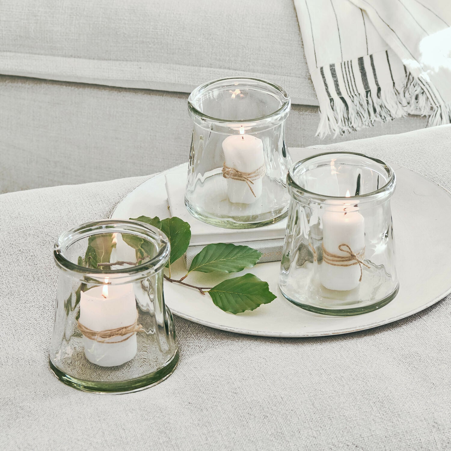Set di 3 portalumini Gravière Set di tre portacandele in vetro con candele bianche e corda naturale su sfondo chiaro