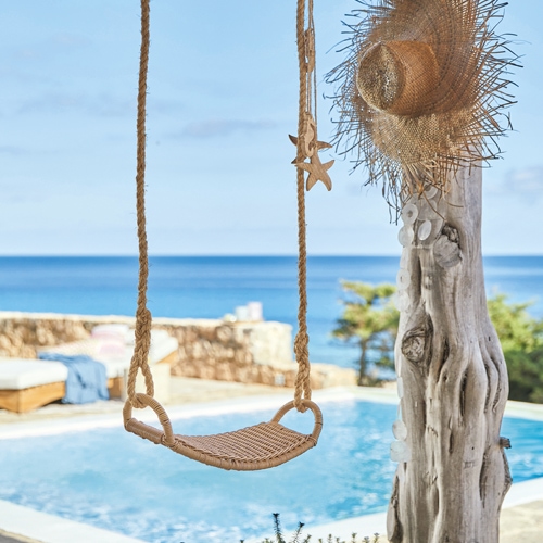 Altalena in corda intrecciata davanti a piscina con vista mare, decorazione estiva