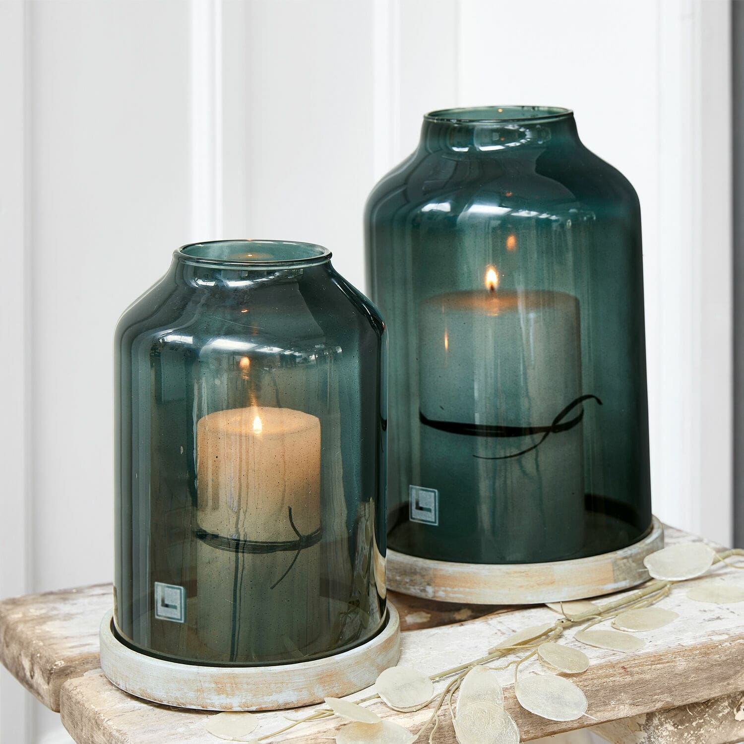 Coppia di portacandele Heavenly Due lanterne in vetro verde con candele bianche su tavolo di legno, decorazione per interni