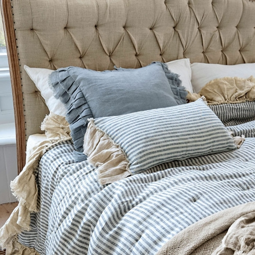 Cuscini in lino beige e blu con coperta a righe su testiera imbottita beige
