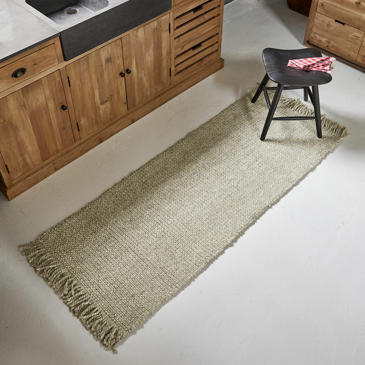 Passatoia Maravéa Tappeto beige con frange in materiale naturale sul pavimento di una cucina con mobili in legno