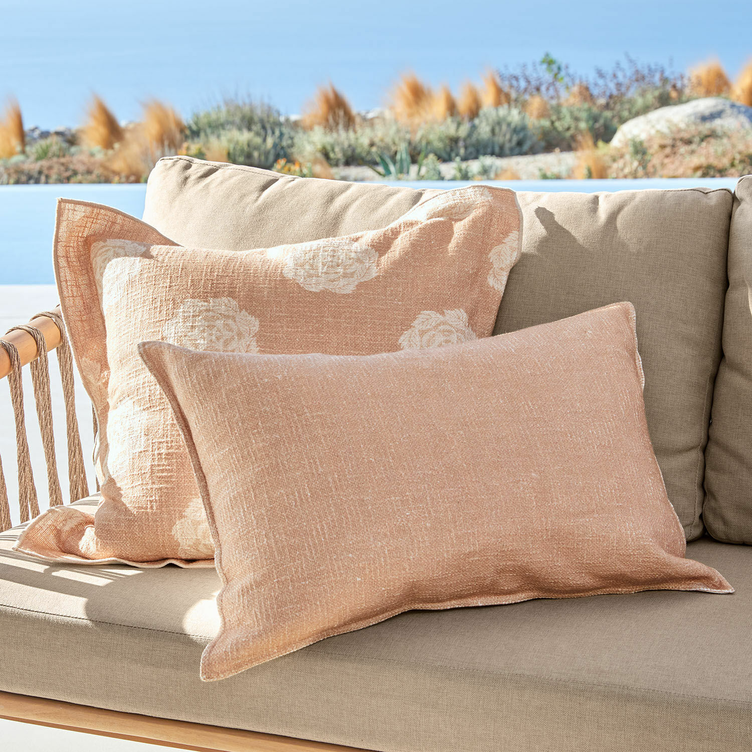 Coppia di copricuscini Belvienne Cuscini decorativi in lino beige su divano beige all'aperto con vista su giardino e cielo