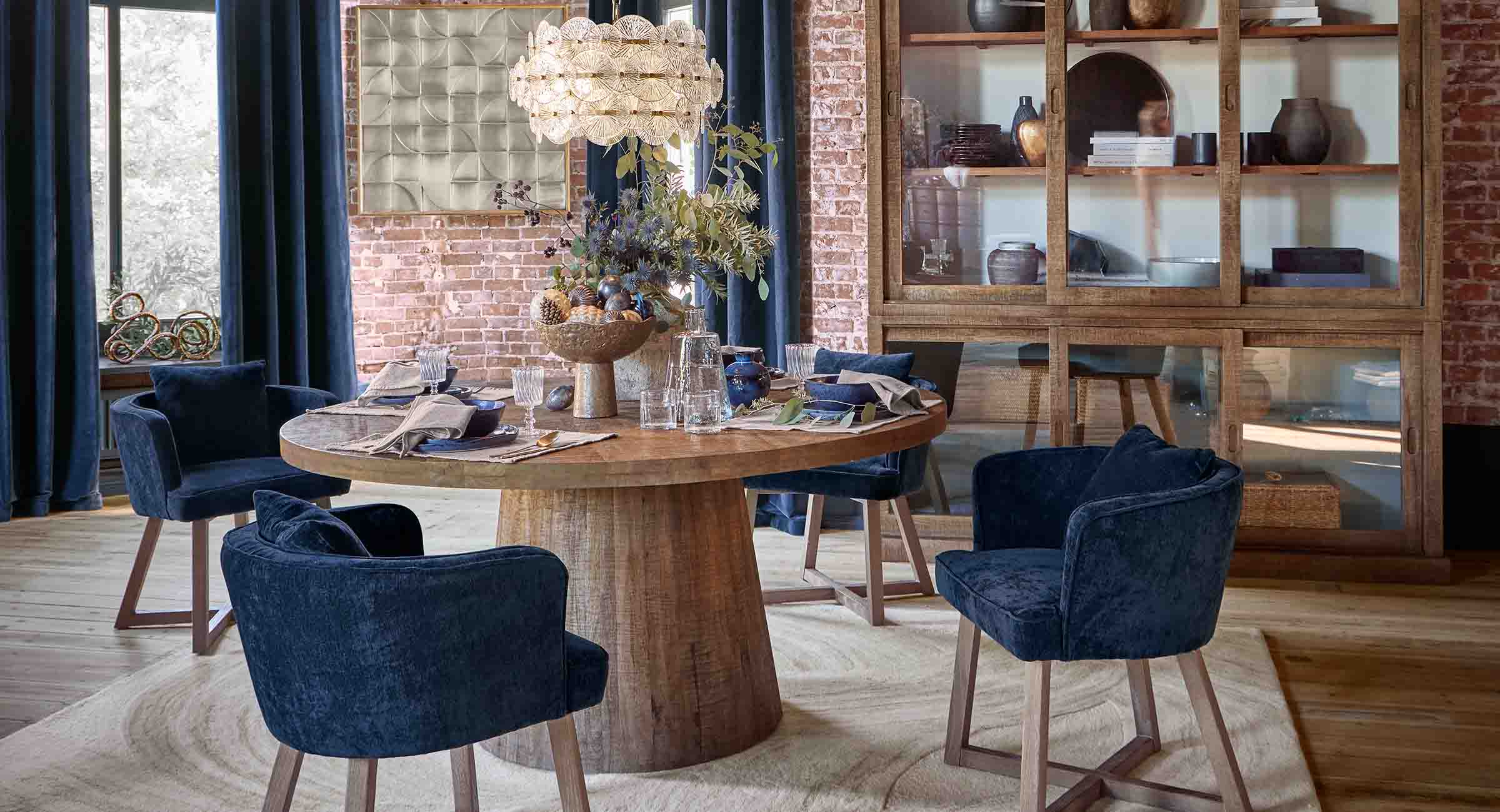 Sala da pranzo con tavolo rotondo in legno e sedie in velluto blu navy in stile loft