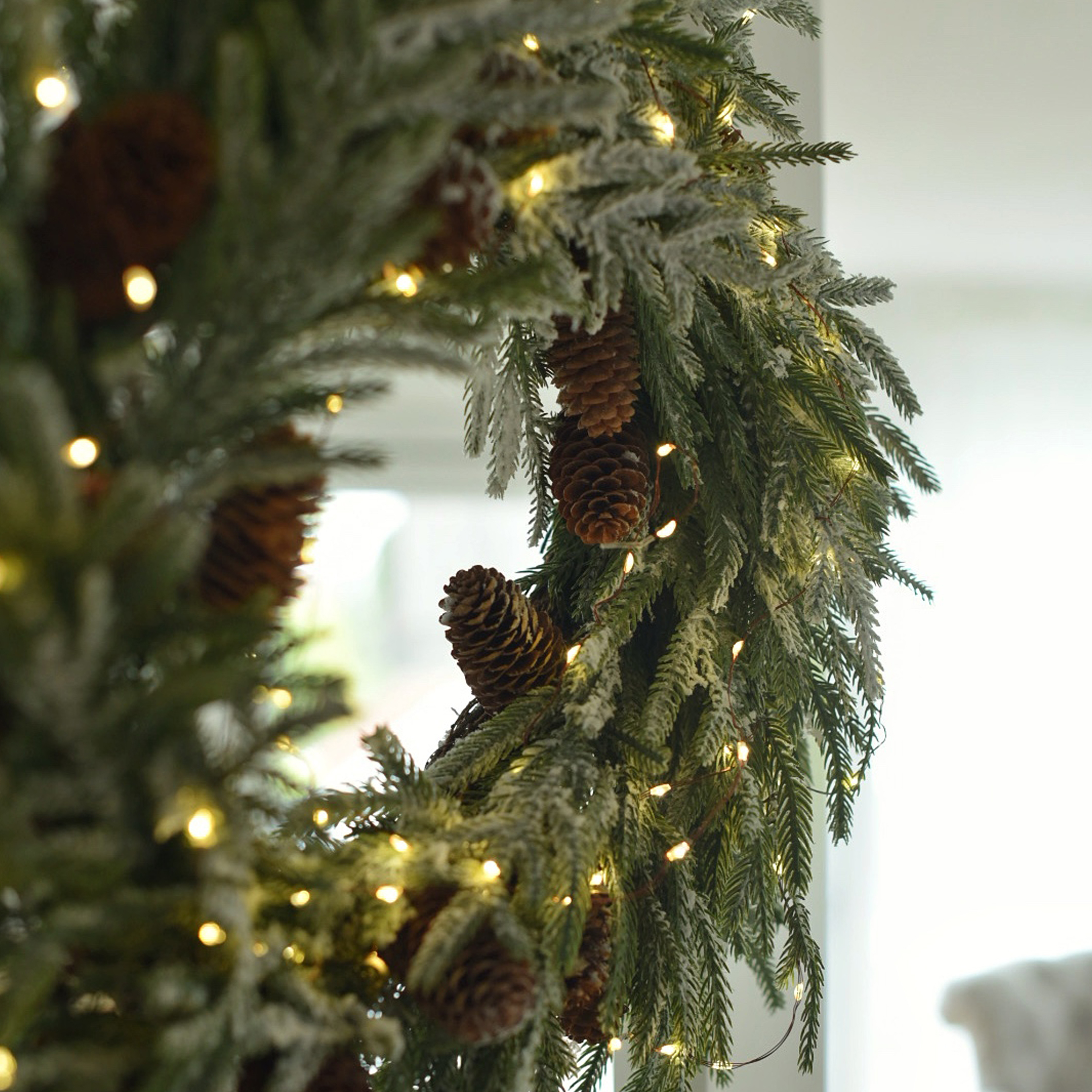 Corona natalizia di rami verdi con pigne e luci LED calde per decorazione invernale