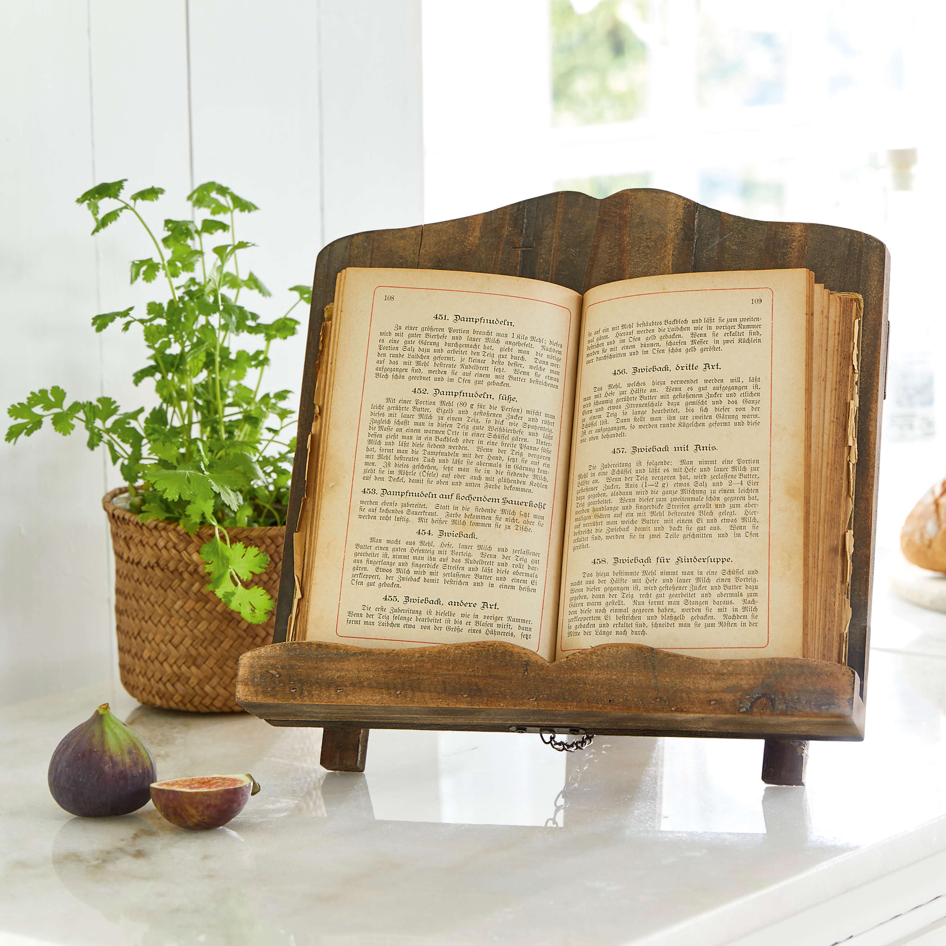 Leggio in legno scuro con vecchio libro di cucina aperto su piano in marmo