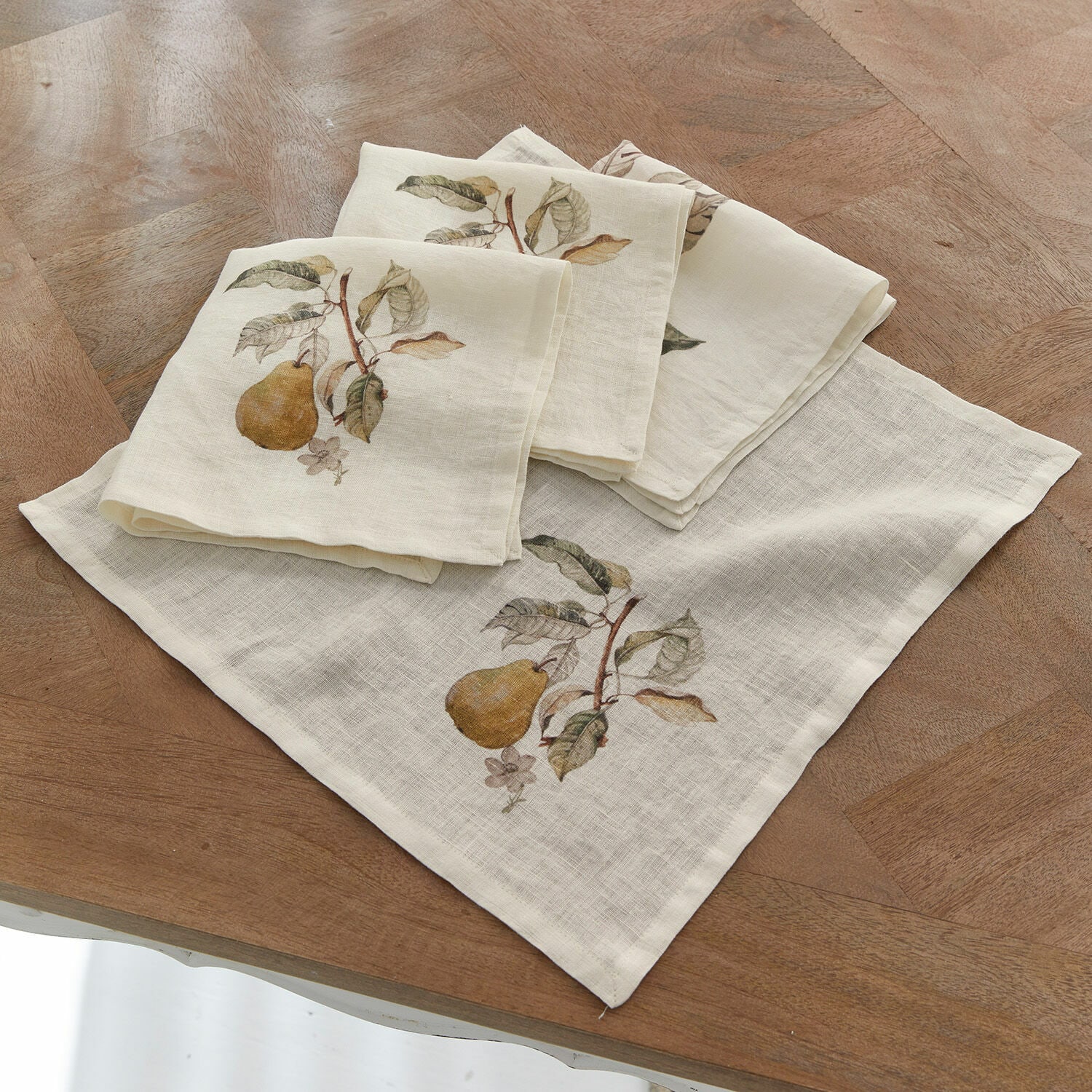 Set di 4 tovaglioli Tupisa Tovaglioli in lino crema con stampa di pera e foglie su tavolo in legno, decorazione tavola