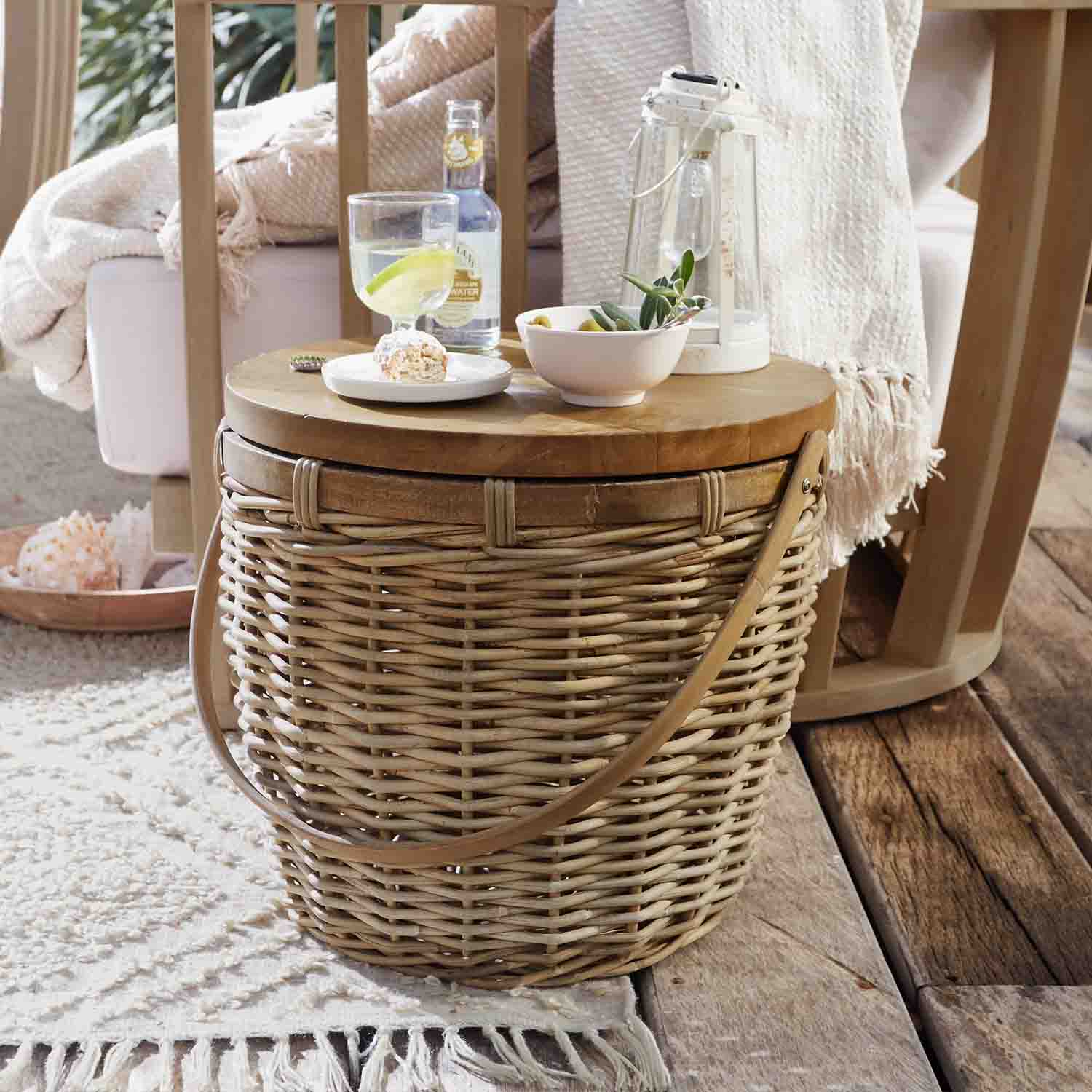 Tavolino rotondo in vimini e legno naturale con lanterna e snack su terrazza in legno rustico