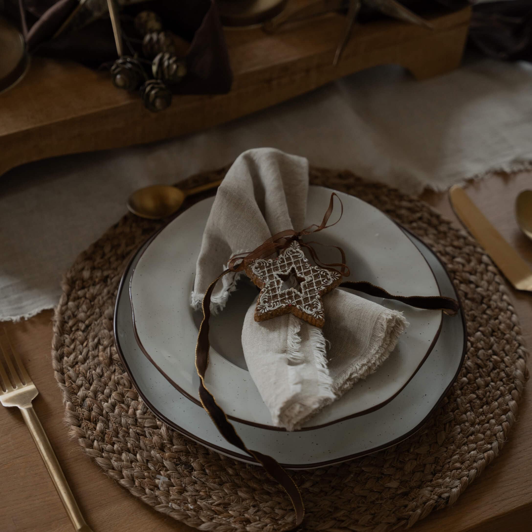Tavola rustica con sottopiatto intrecciato, piatto bianco e tovagliolo di lino con decorazione a stella
