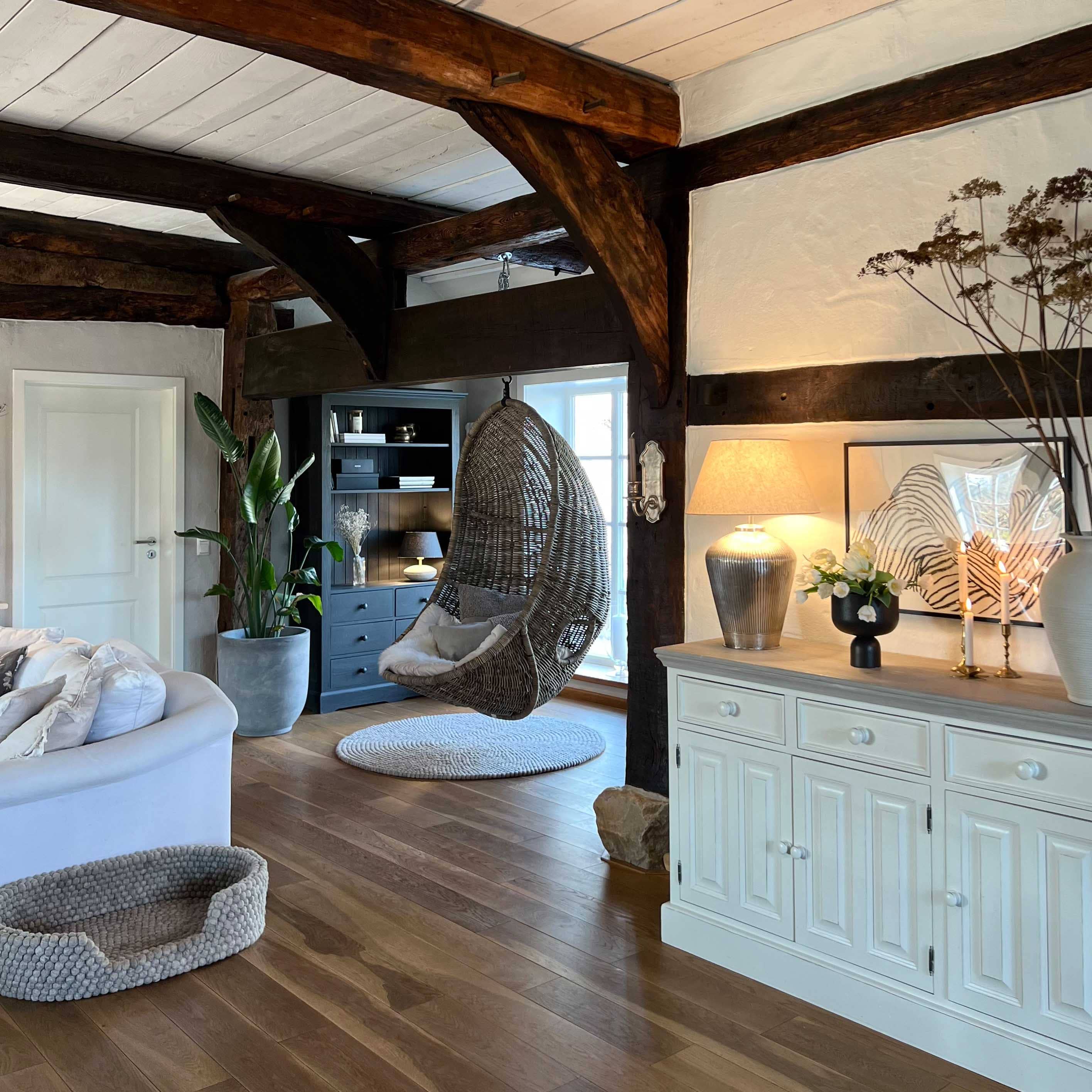 Sedia sospesa in rattan grigio in soggiorno accogliente con pavimento in legno e credenza bianca